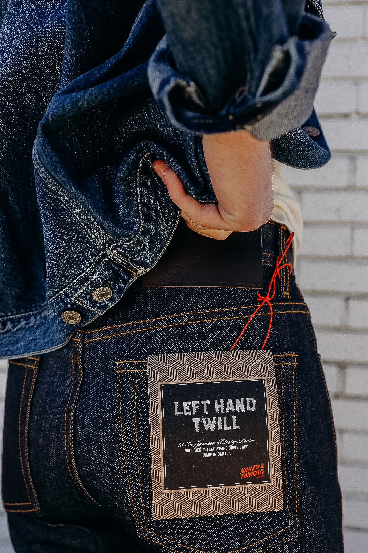 Close-up of person in dark denim jeans and jacket showing Left Hand Twill Japanese selvedge denim label