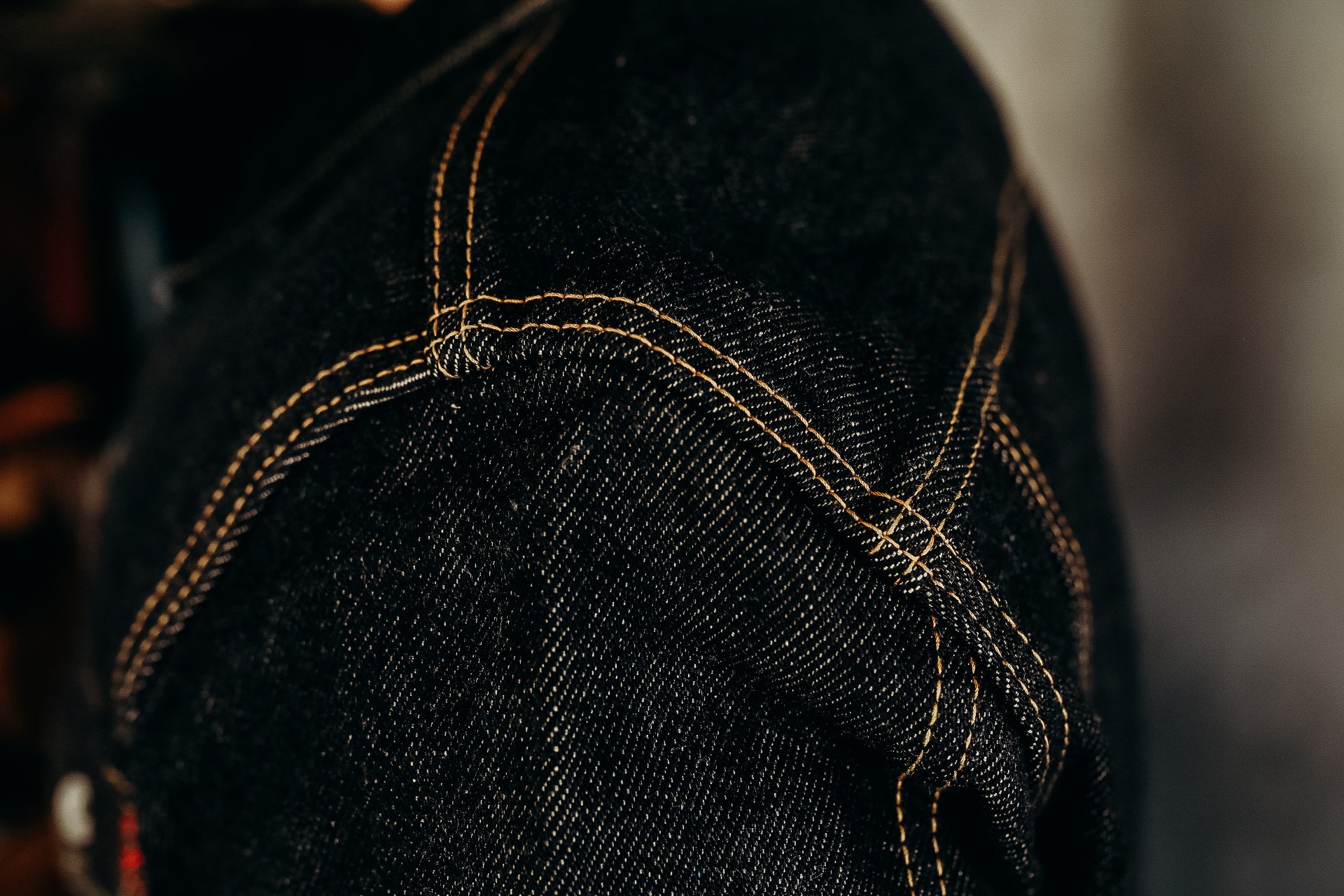 Close-up of durable black denim fabric with detailed orange stitching from Iron Shop Provisions jeans