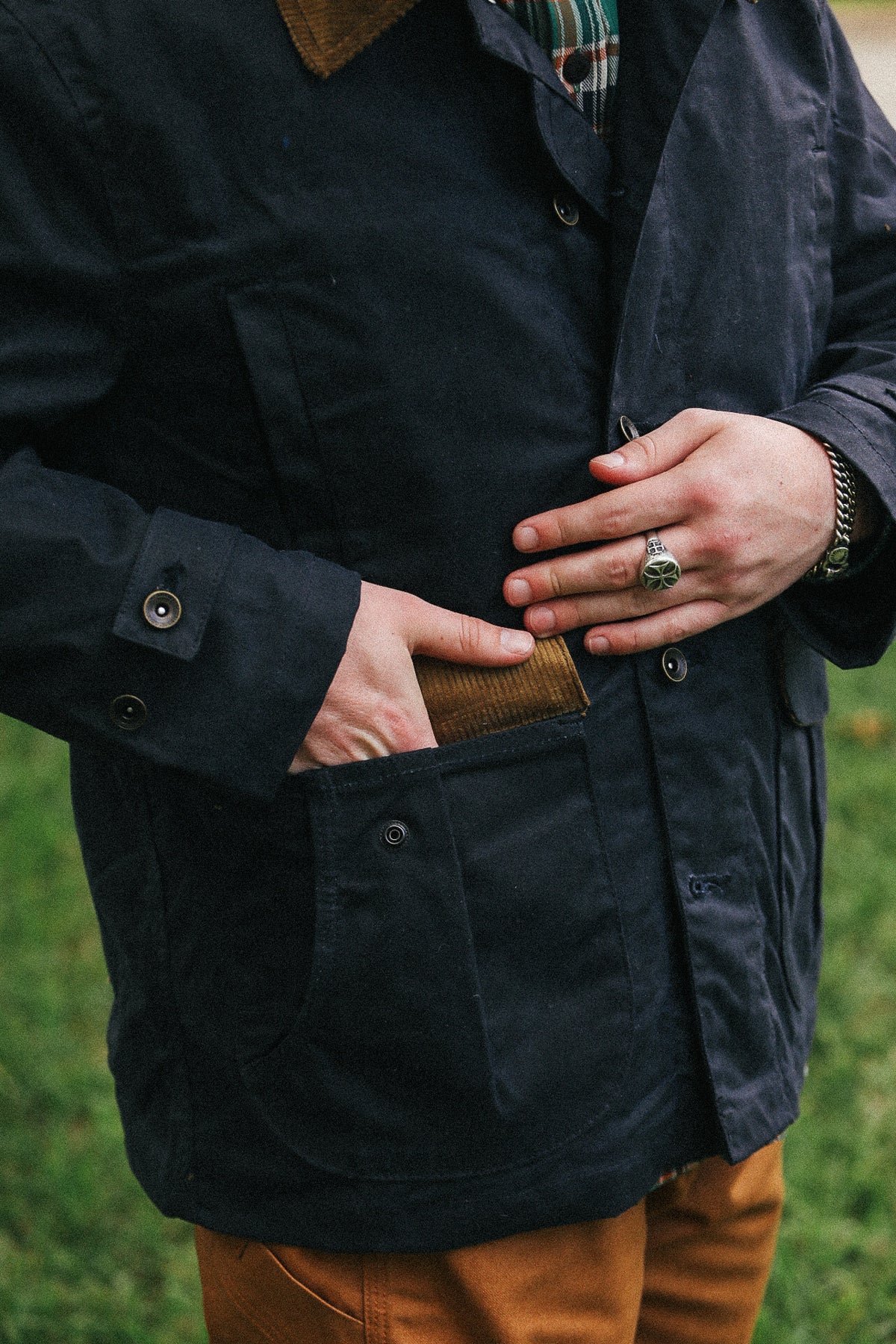 man with black jacket with showing pocket detail against a green natural background
