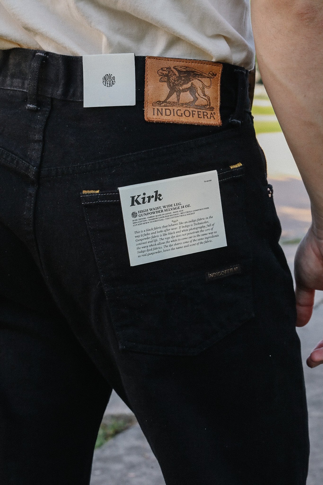 Close-up of black Indigofera Kirk high waist wide leg jeans with leather logo patch and product tags