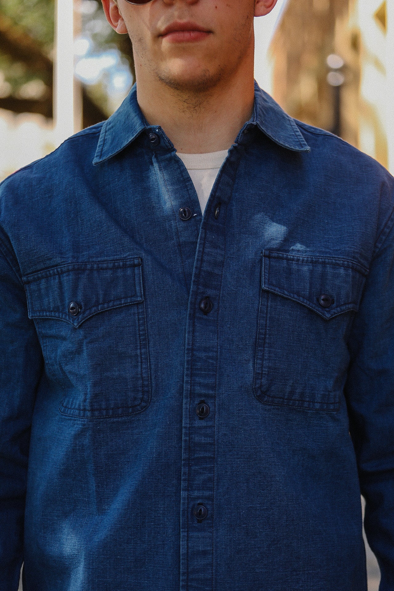 Close-up of man wearing blue denim work shirt with buttoned chest pockets from Iron Shop Provisions