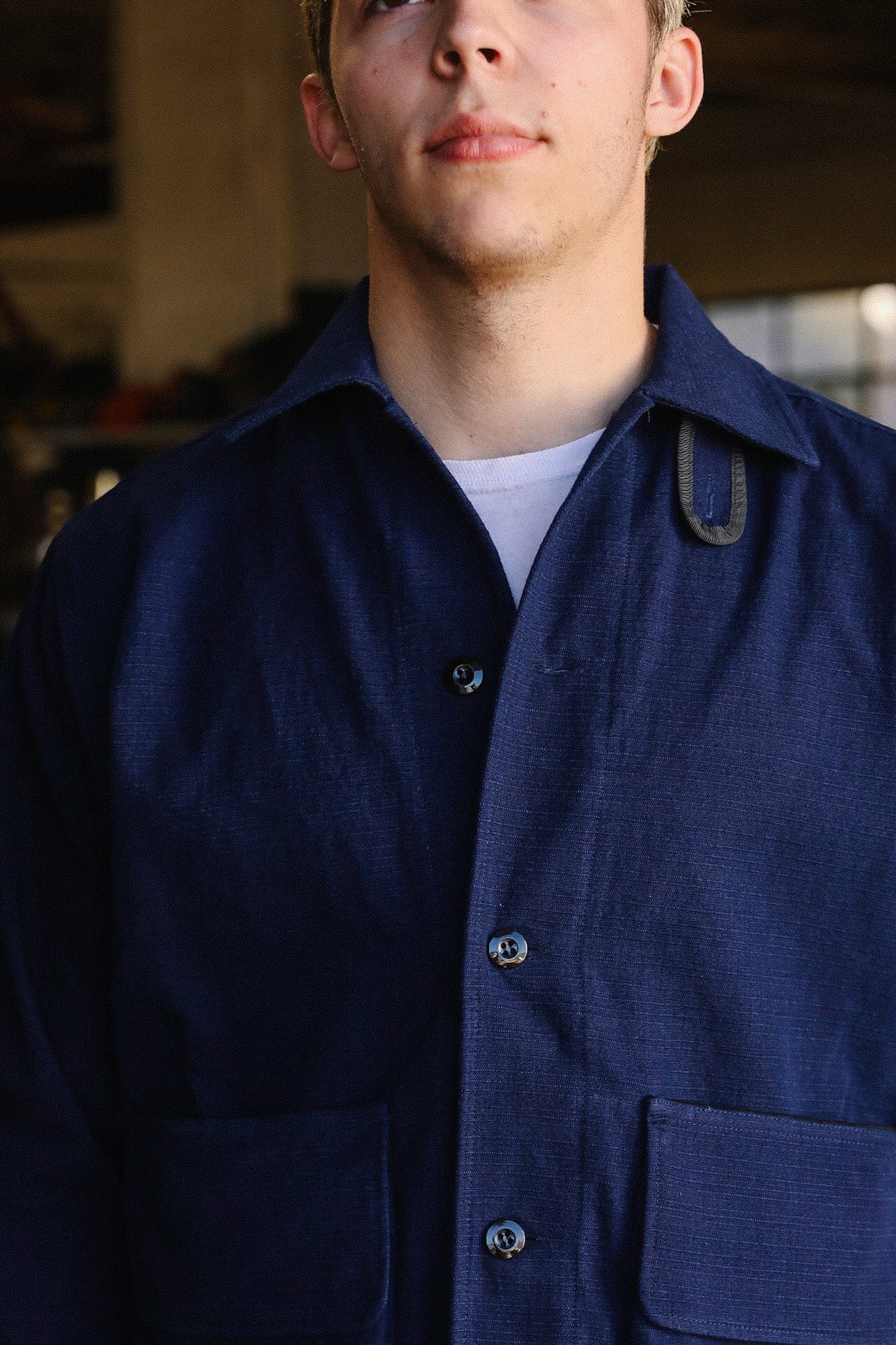 Close-up of a man wearing a navy blue button-up work jacket with patch pockets over a white shirt