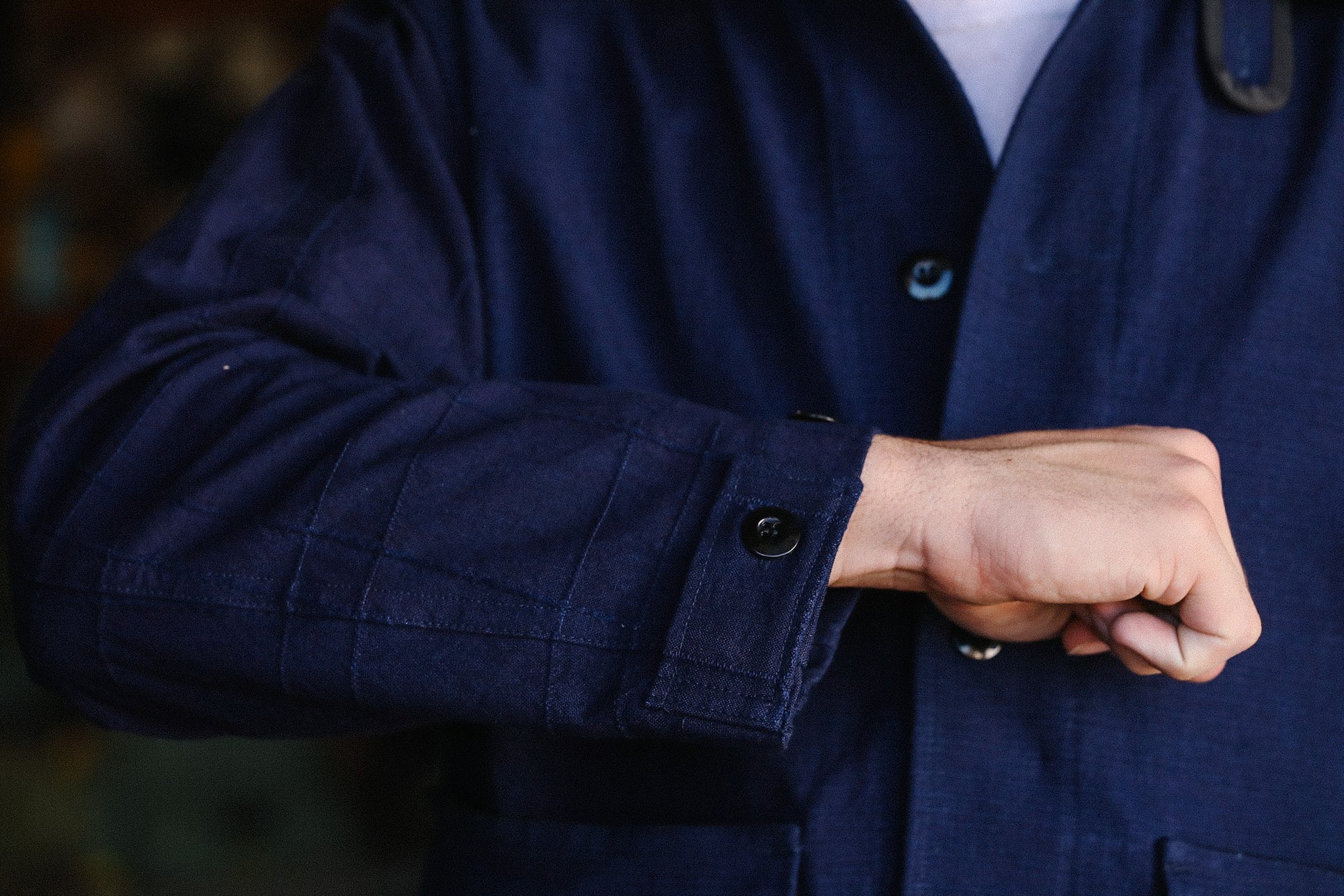 Close-up of person wearing navy blue work jacket with buttoned cuff at Iron Shop Provisions