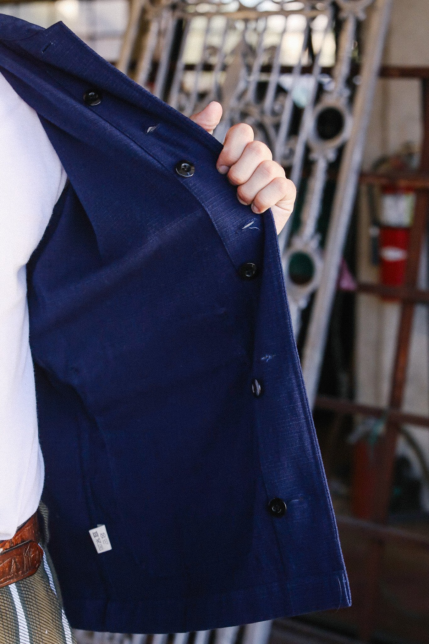 Person holding open a navy blue button-up jacket revealing button details and interior lining
