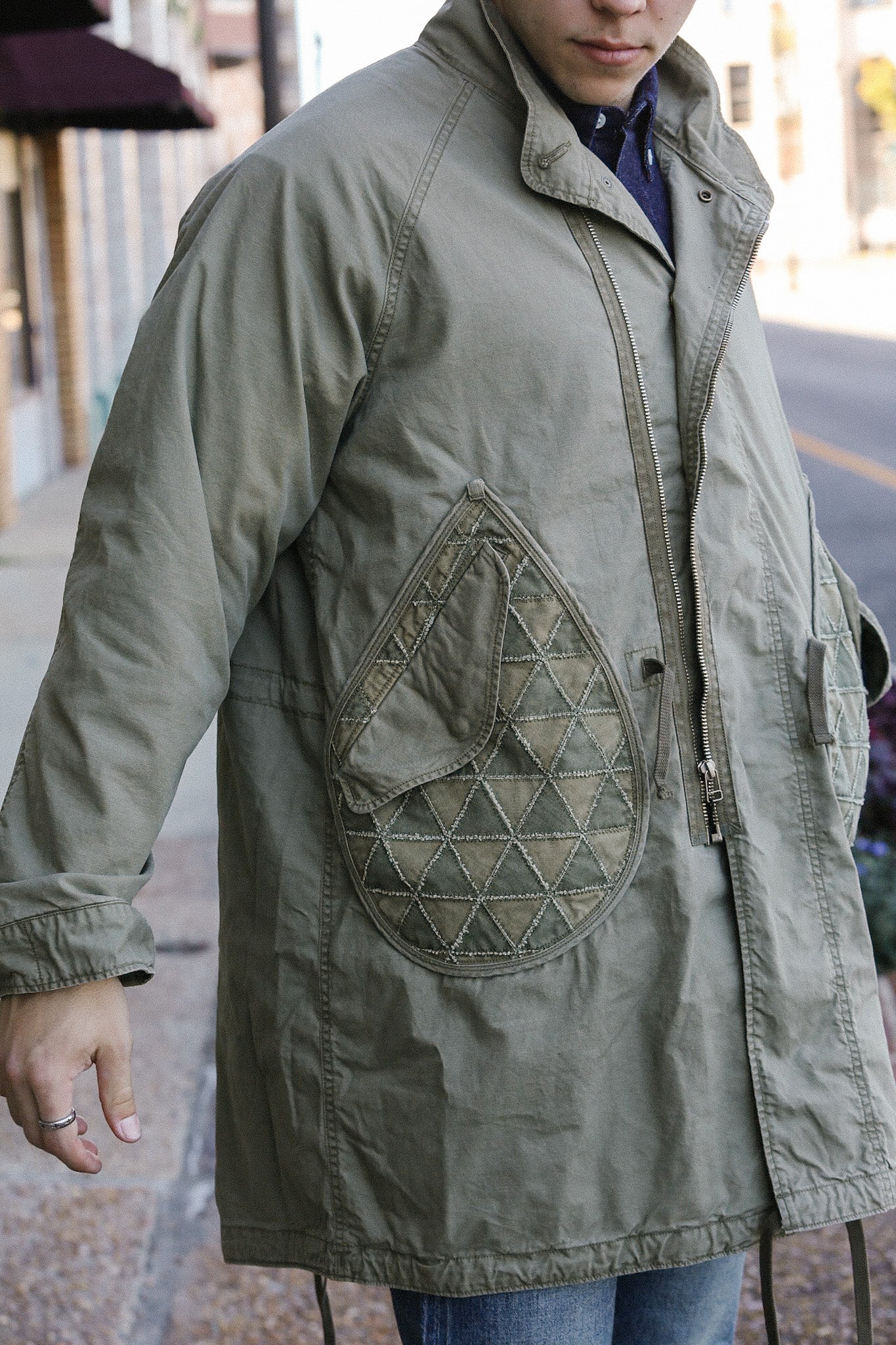 Man wearing olive green military-style jacket with quilted diamond patch pockets on street