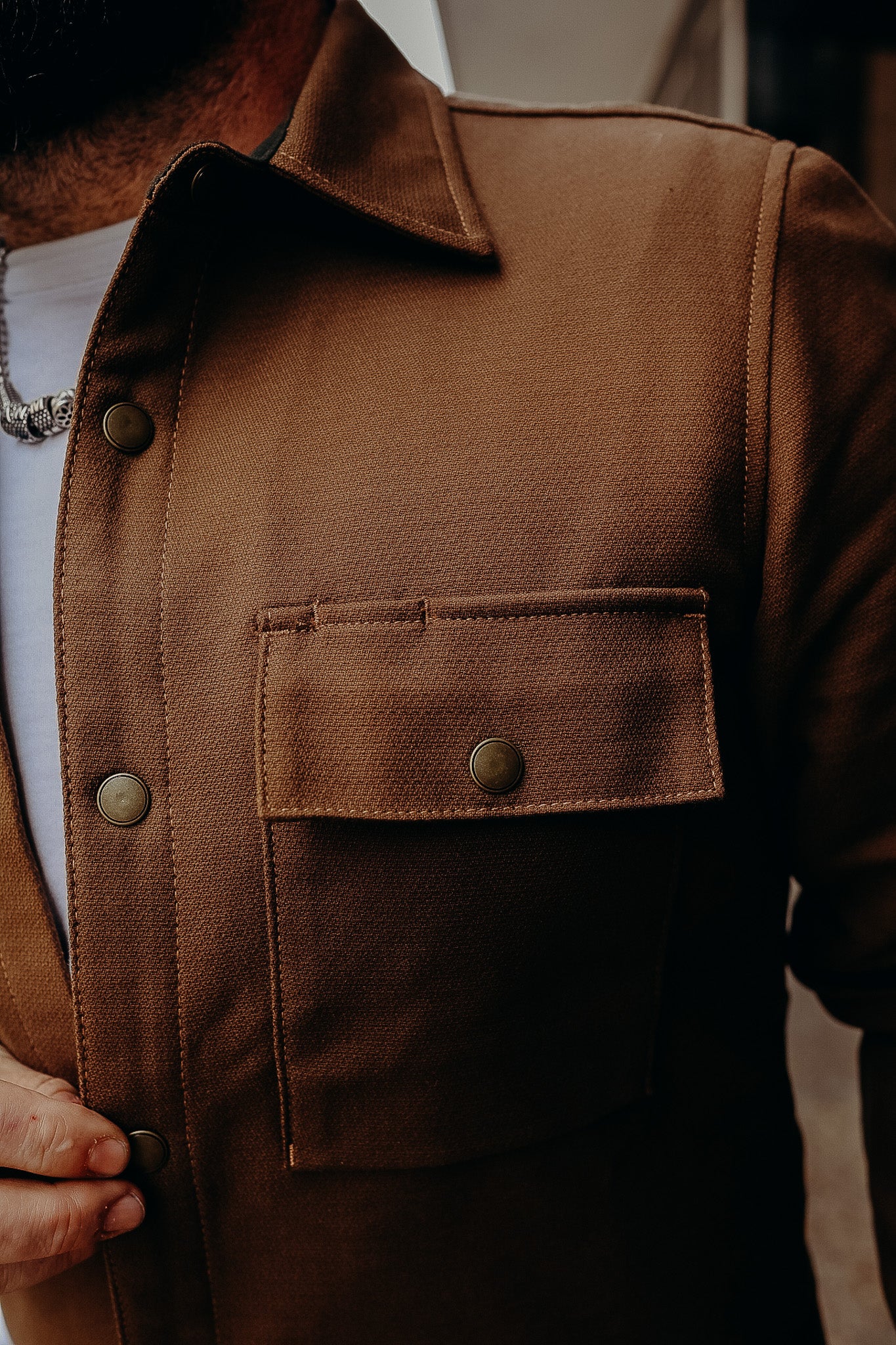 Close-up of a brown button-up work jacket with pocket flap and brass snaps at Iron Shop Provisions