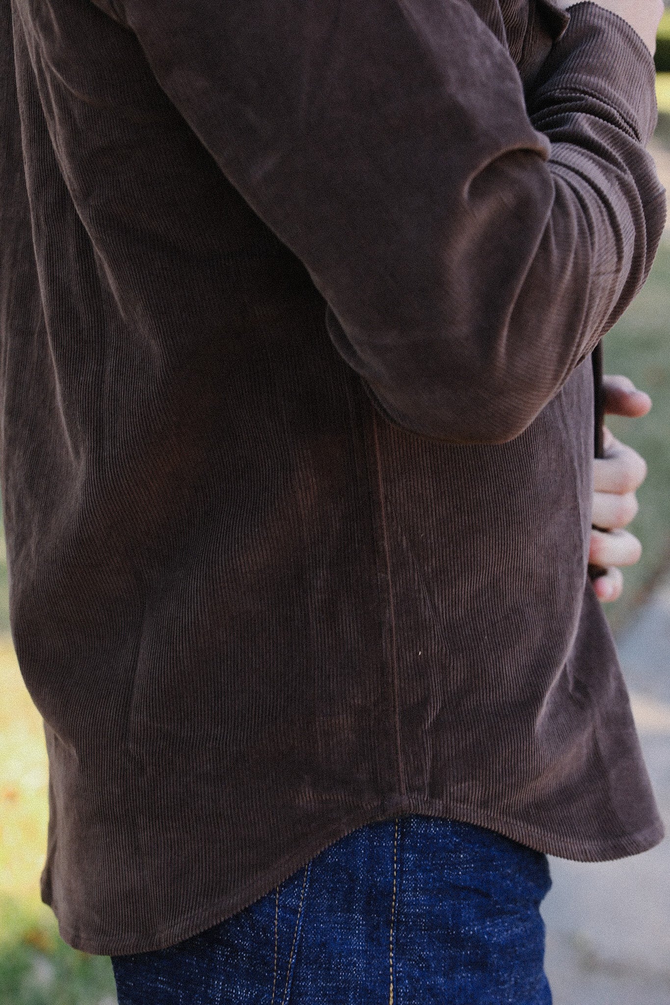 Close-up of person wearing brown corduroy shirt and blue denim jeans outdoors