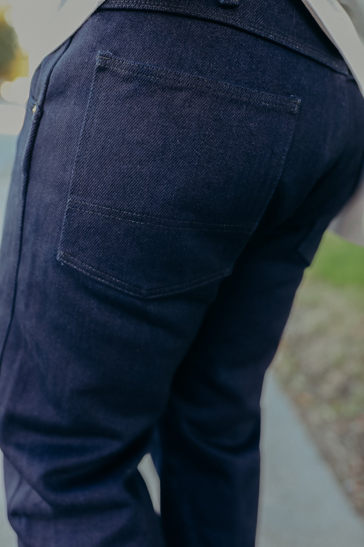 Close-up of durable dark blue denim jeans back pocket with detailed stitching in outdoor setting