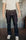 Man wearing dark raw denim jeans with contrast stitching and white sneakers on industrial floor
