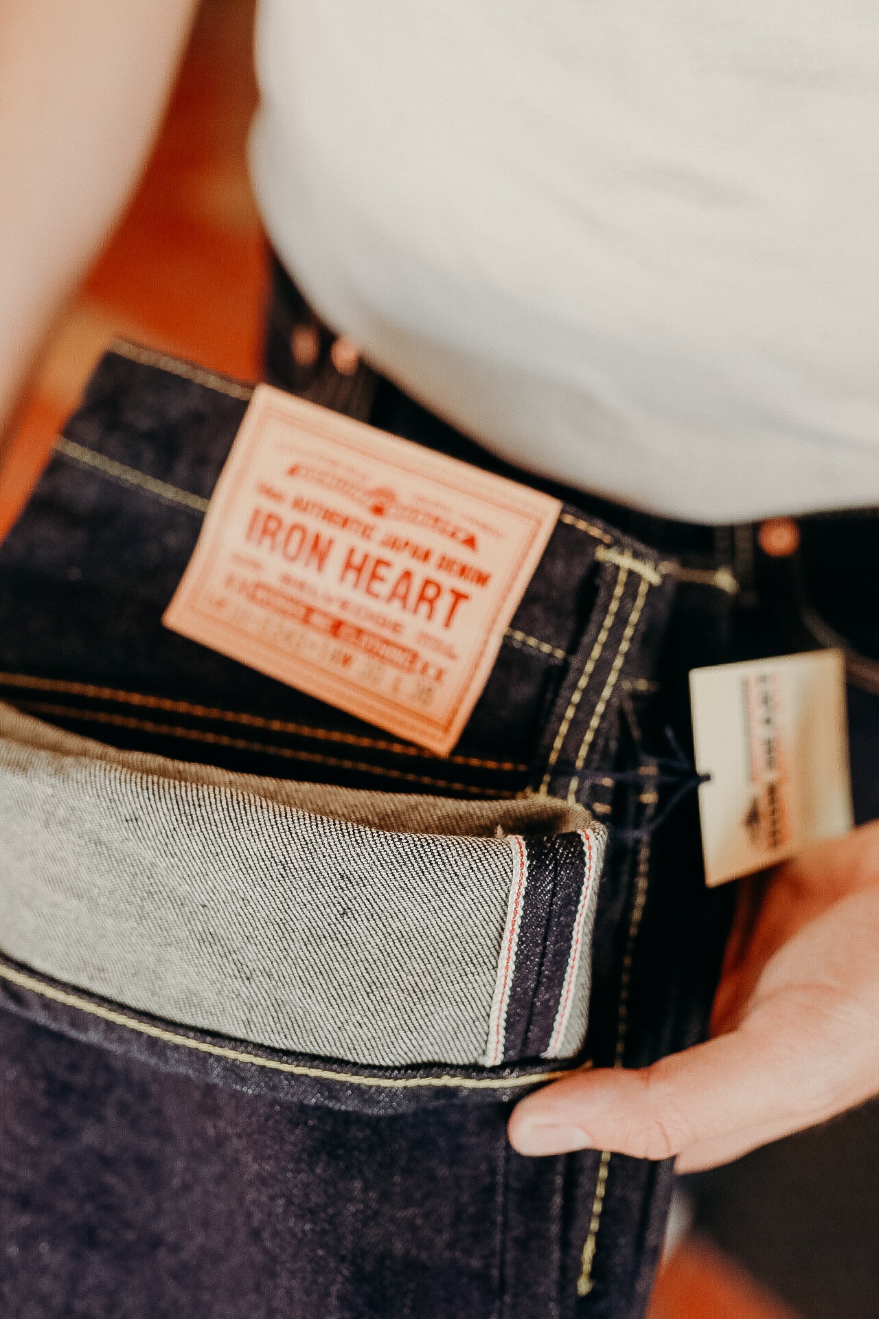 Close-up of raw selvedge denim jeans with Iron Heart leather patch and hanging tag