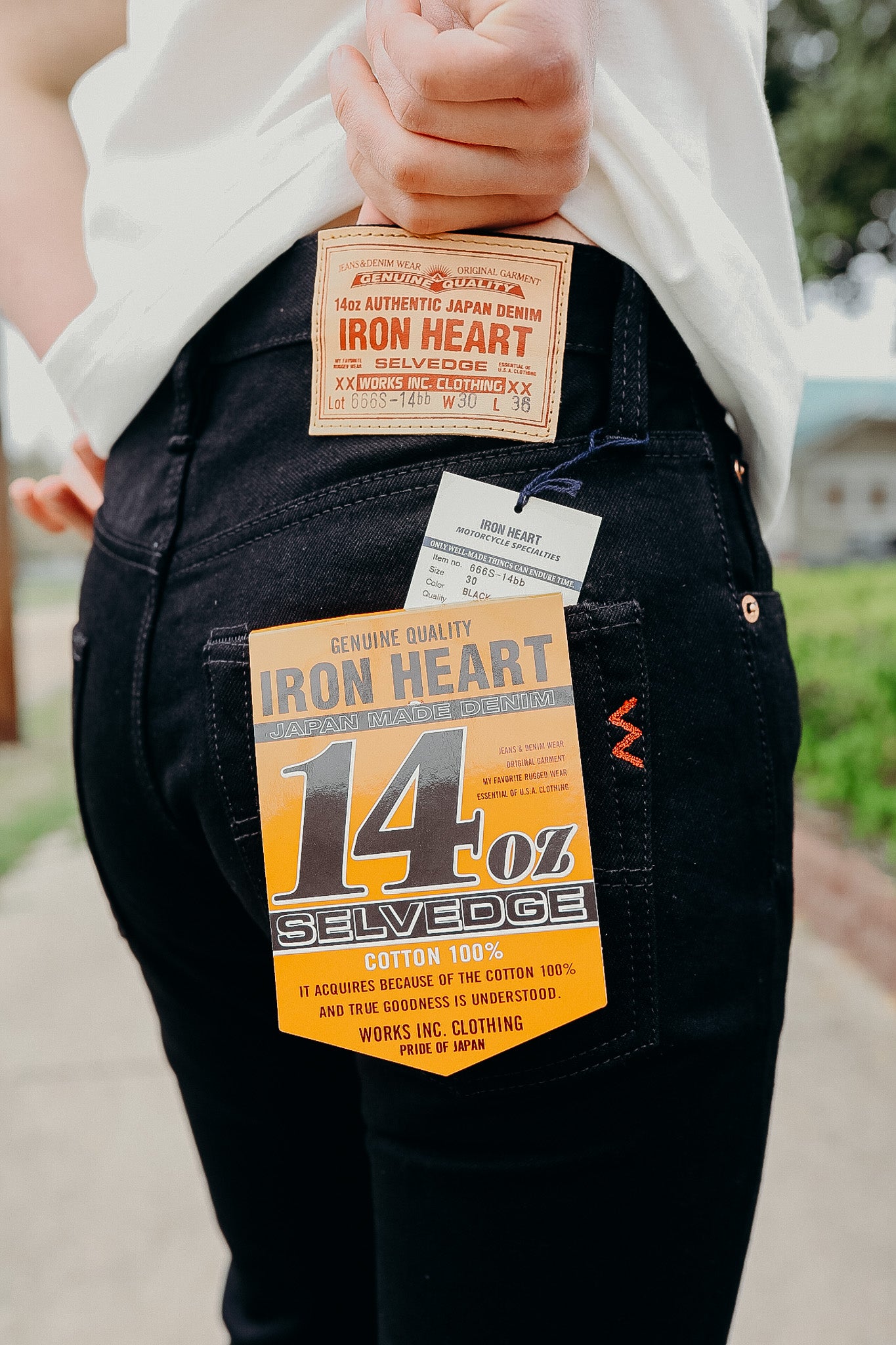 Close-up of Iron Heart black 14oz selvedge denim jeans with brand labels on the back pocket and waistband