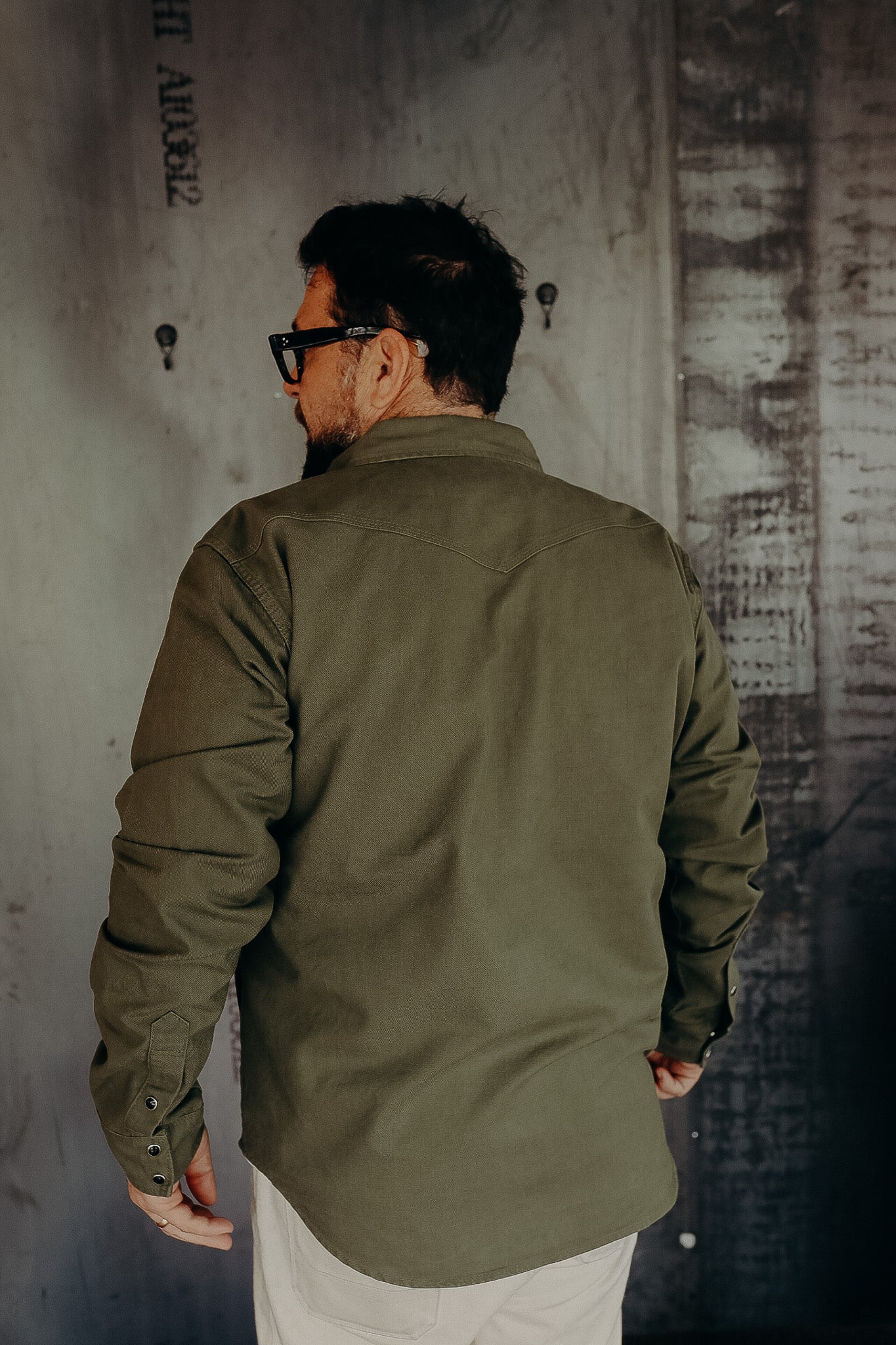 Man wearing olive green durable work shirt from Iron Shop Provisions in industrial setting