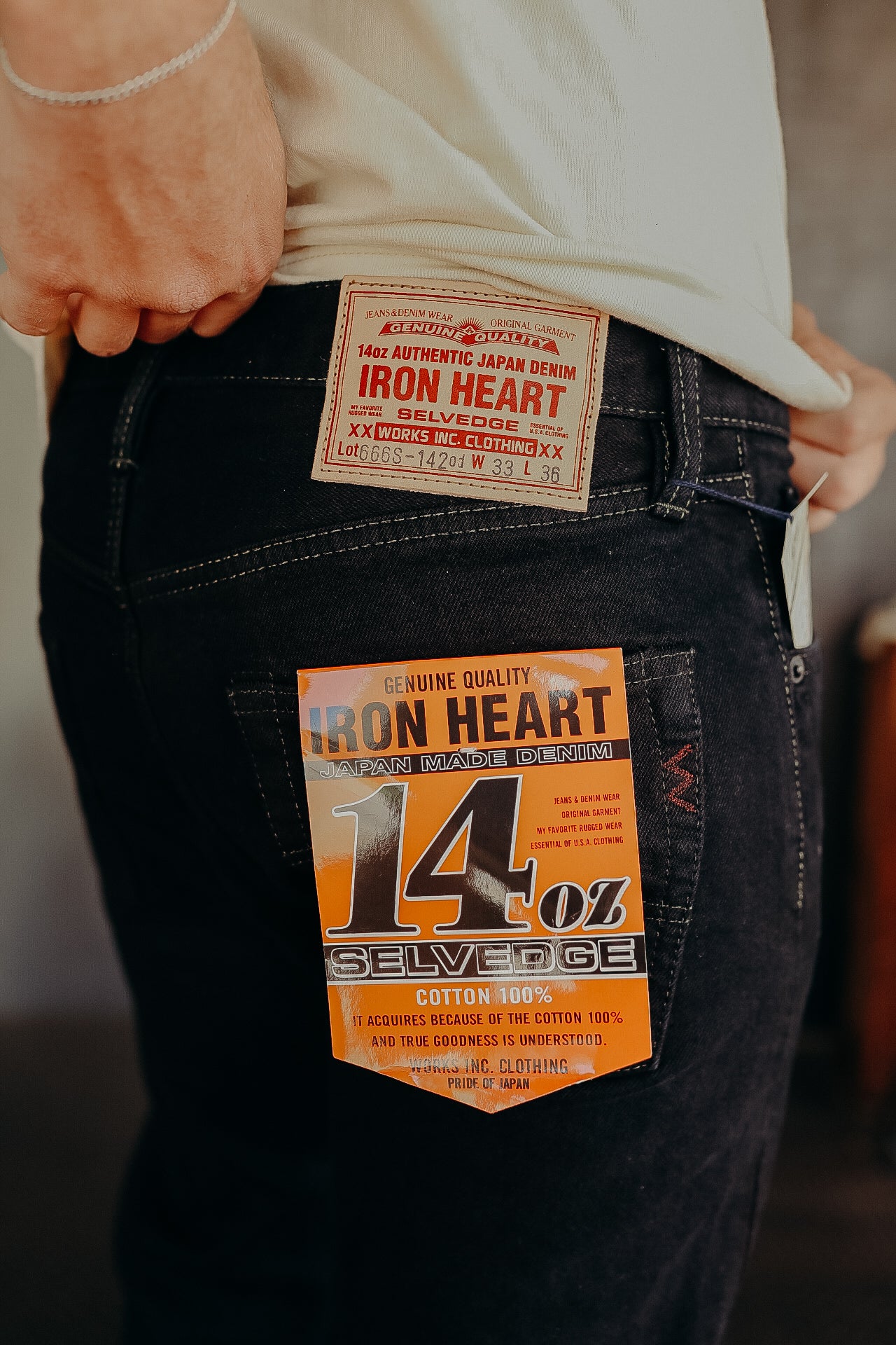 Close-up of person wearing Iron Heart 14oz authentic Japan selvedge denim jeans with leather and paper tags