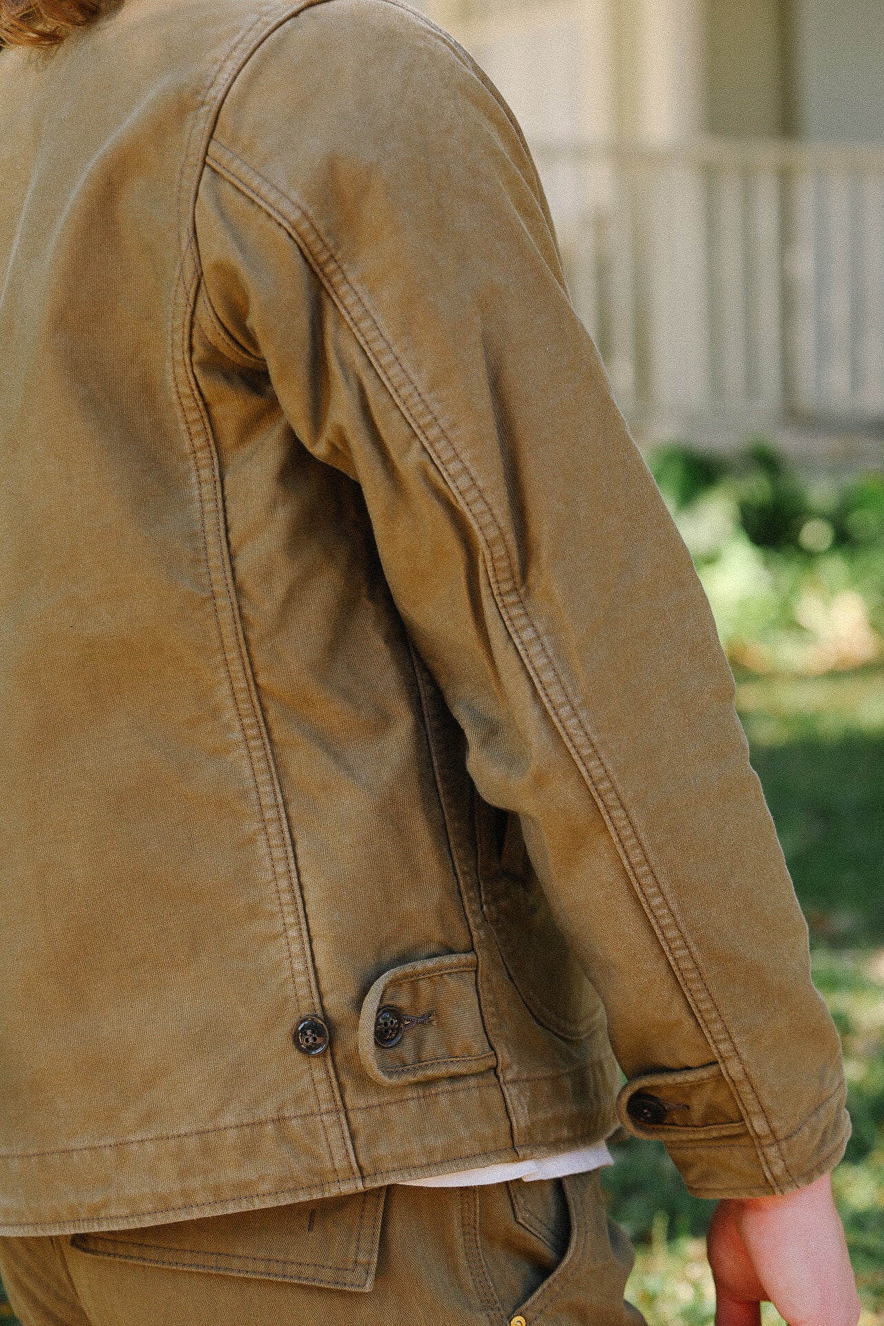 close-up of brown durable work jacket sleeve and side with visible stitching and buttons outdoors