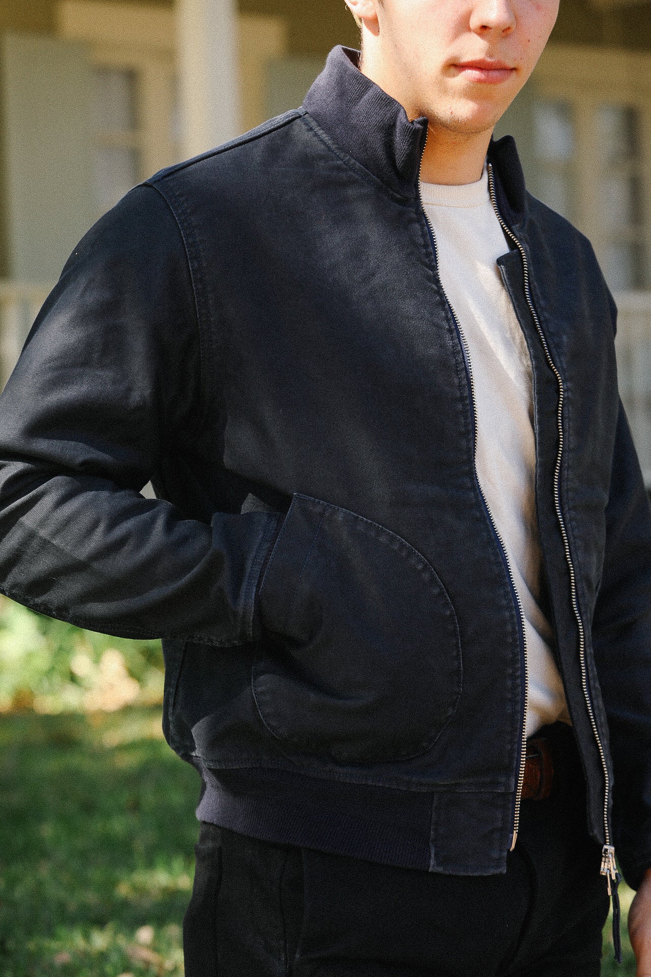 Man wearing navy blue zipped casual jacket with large side pockets over white shirt outdoors