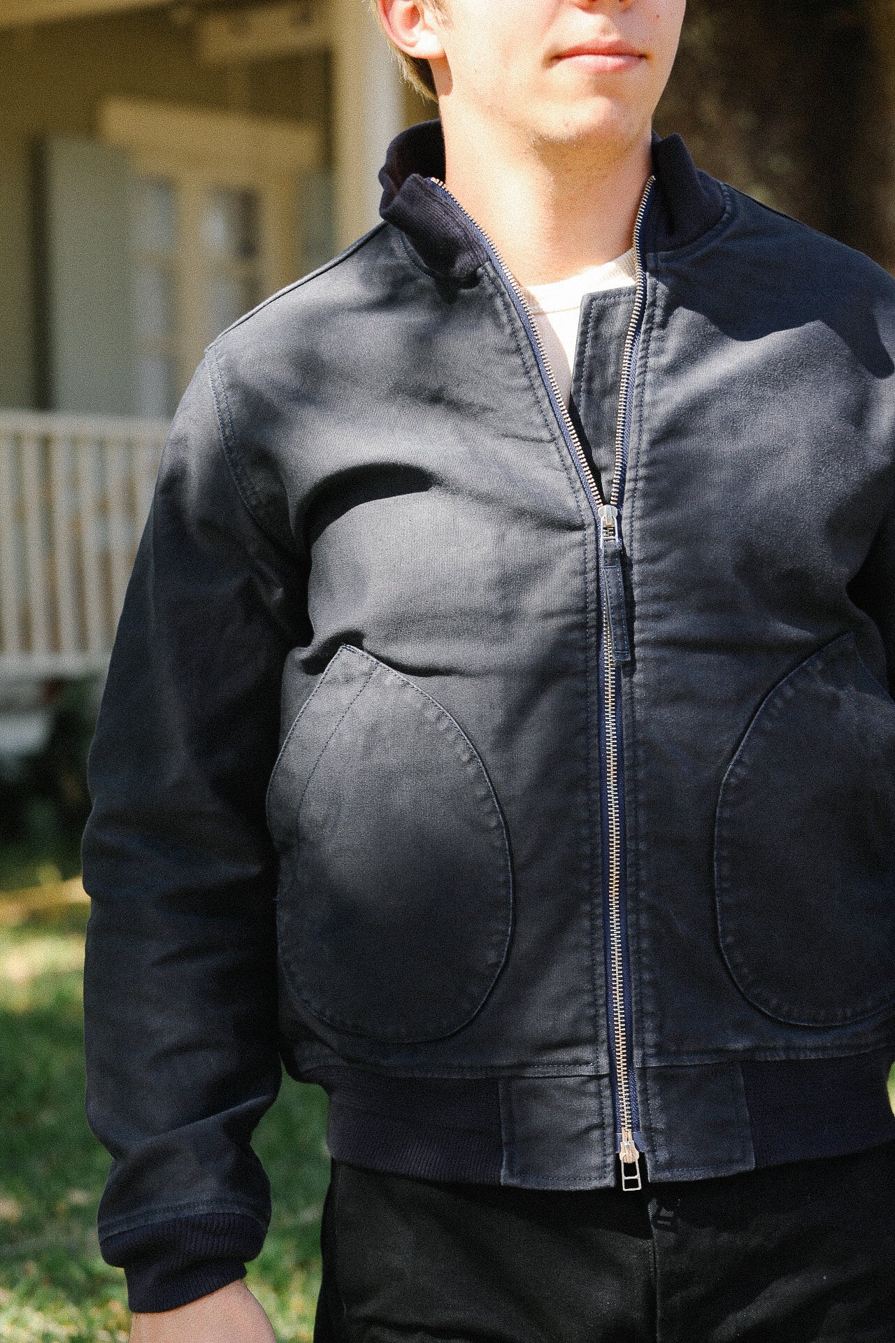 Close-up of man wearing navy blue zip-up work jacket with large front pockets outdoors