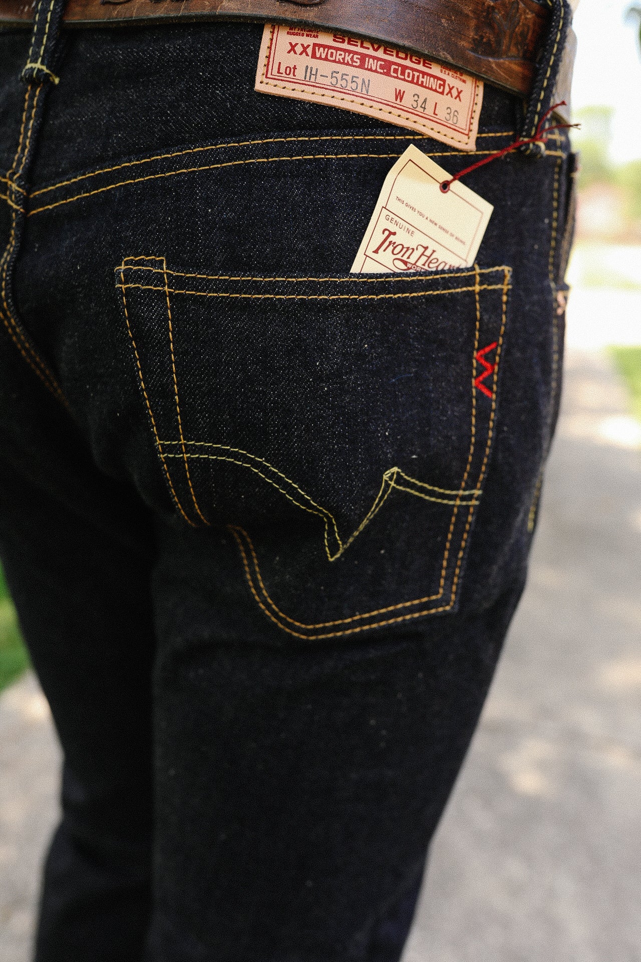 Close-up of Iron Heart dark selvedge denim jeans with leather patch and branded pocket tag outdoors