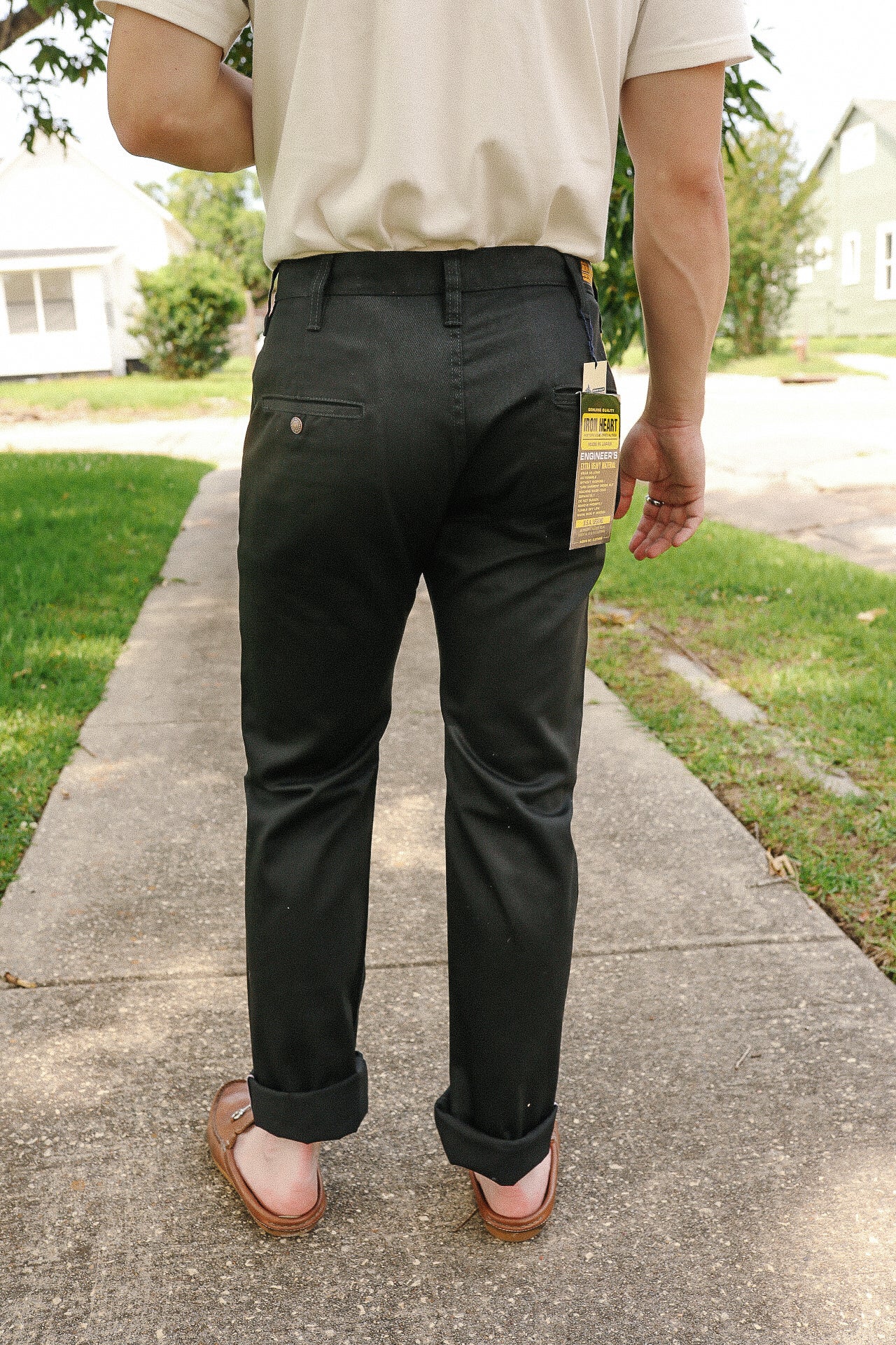 Person wearing black Iron Heart pants with rolled cuffs and brown loafers walking on a sidewalk