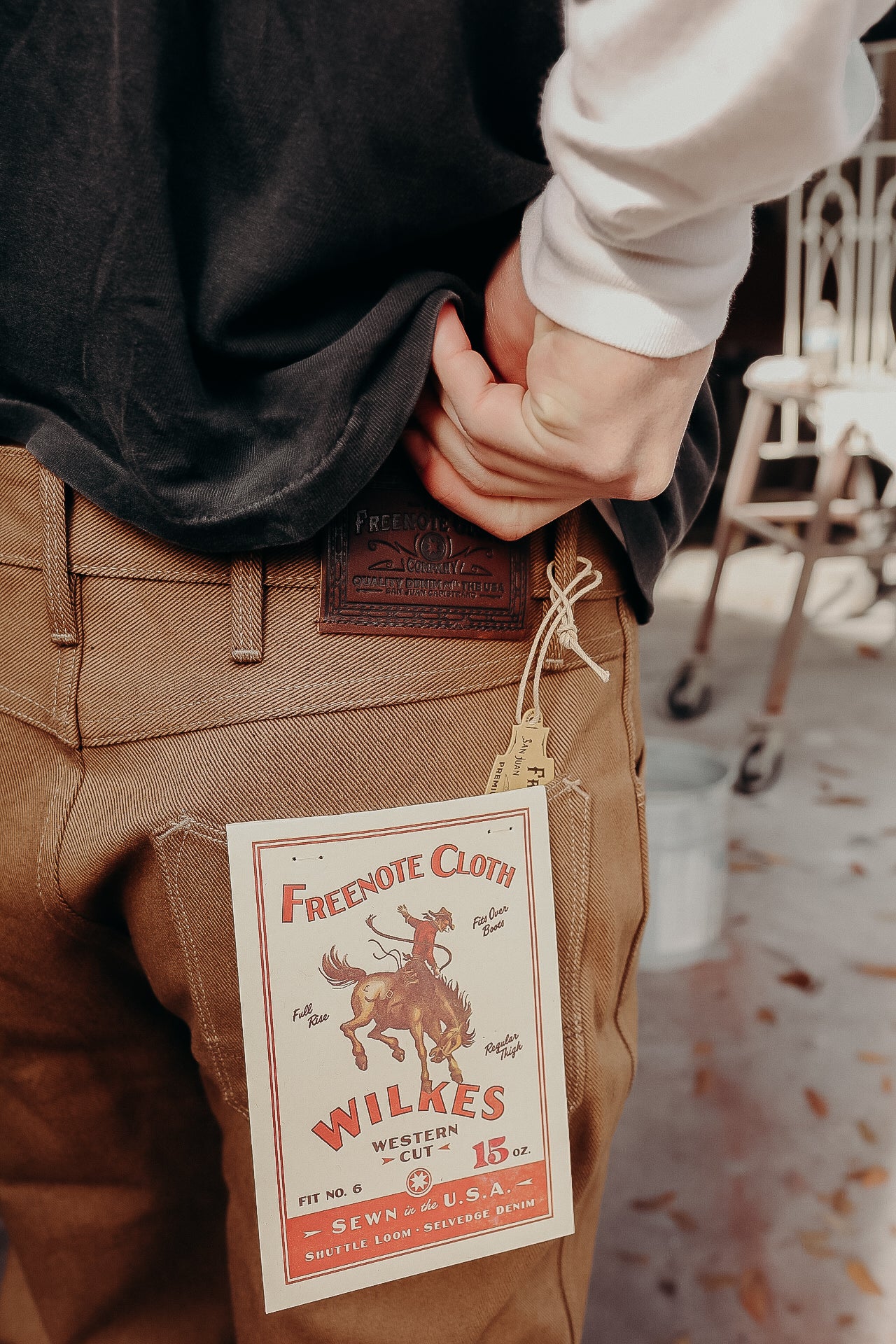 Close-up of brown Freenote Cloth Wilkes Western Cut denim jeans with leather patch and tag on back pocket