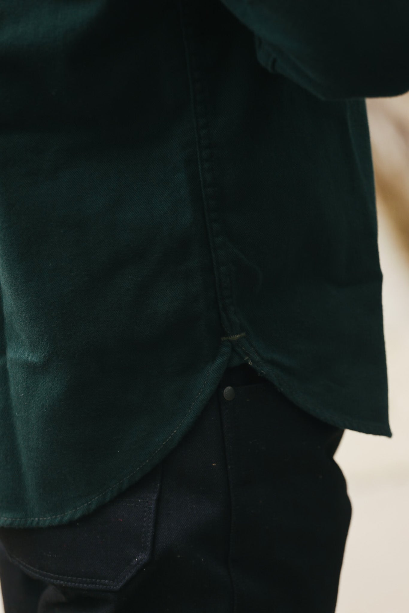 Close-up of dark green ironwork shirt hem over black sturdy work pants