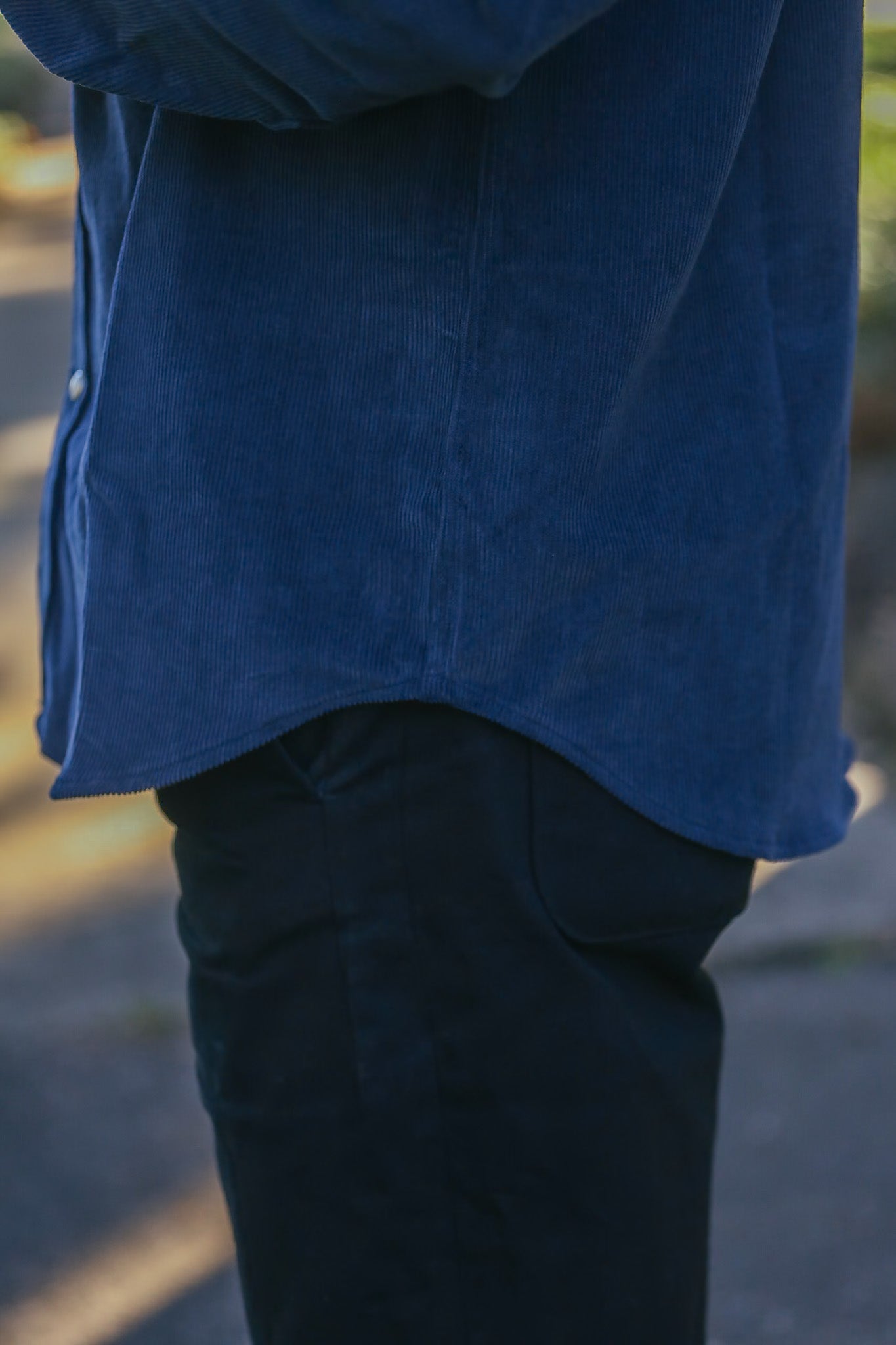 Close-up of person wearing blue corduroy shirt and black pants outdoors at Iron Shop Provisions