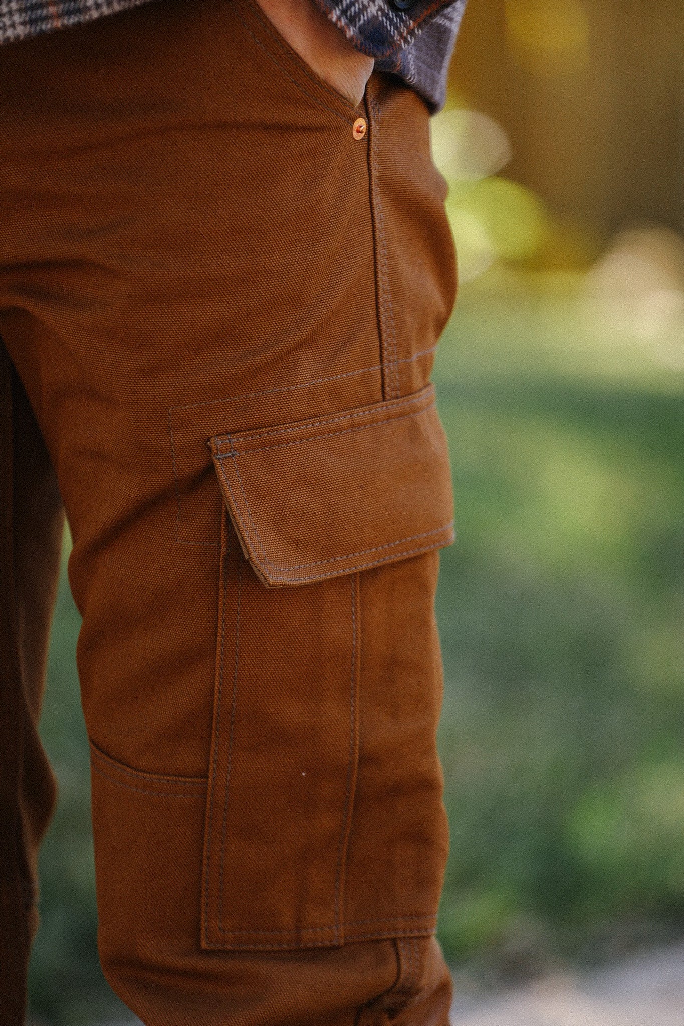 Close-up of brown rugged work pants with side cargo pocket, outdoor setting
