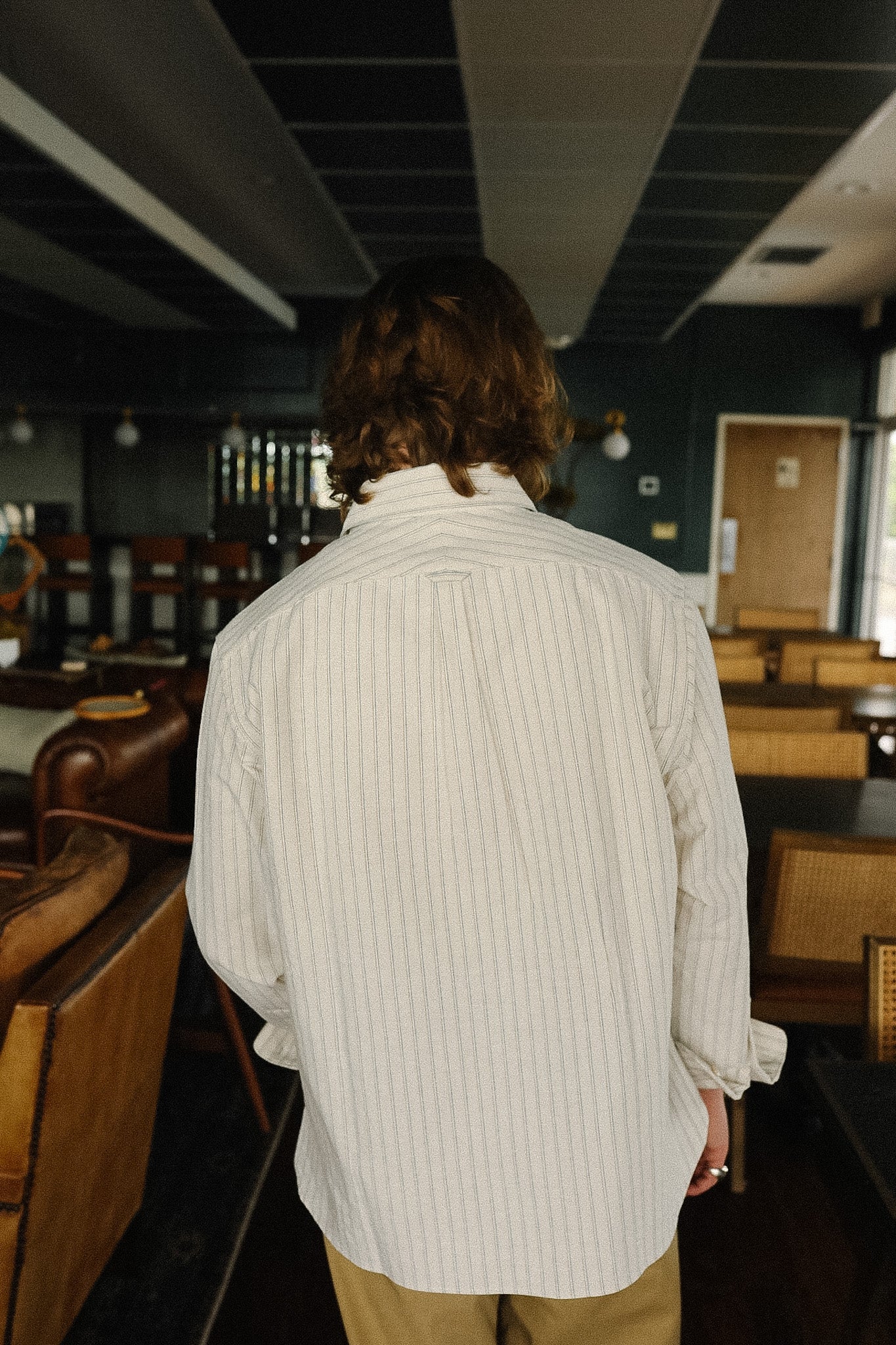 Person wearing a white ribbed sweater in an indoor setting with wooden furniture.
