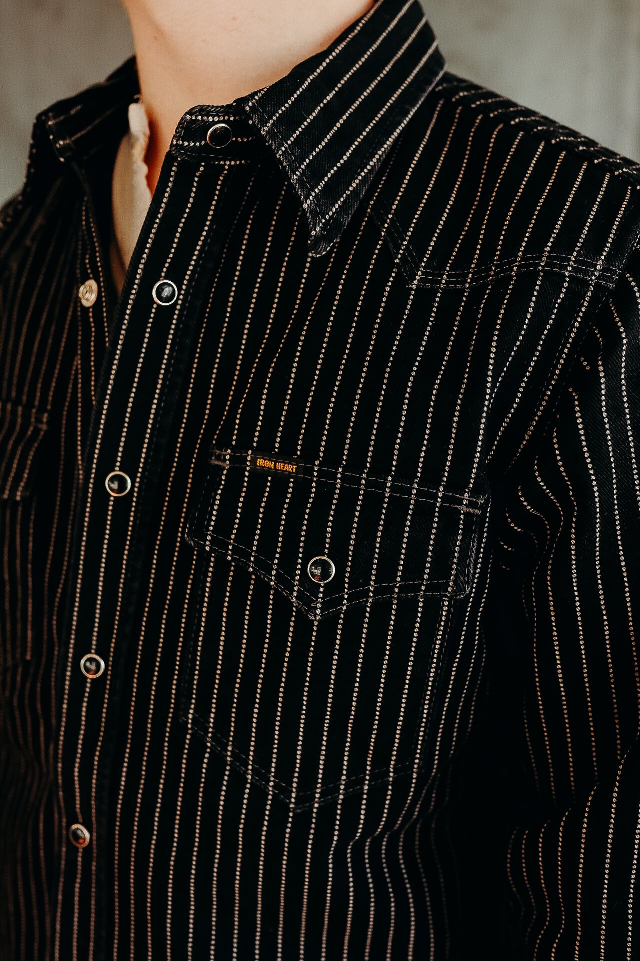 Close-up of a black striped Iron Heart shirt with snap buttons and a chest pocket detail