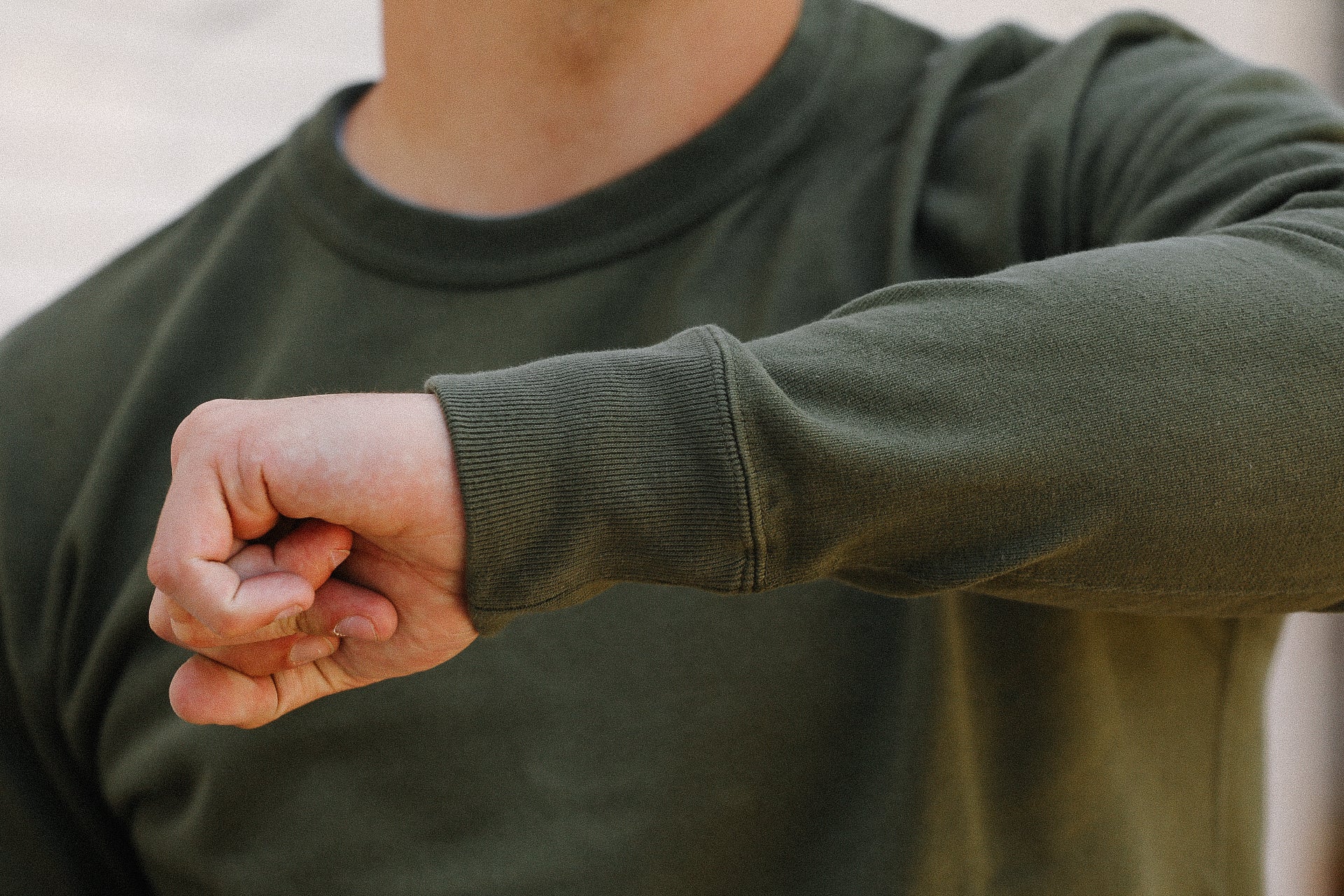 Close-up of person wearing olive green long sleeve shirt with ribbed cuffs