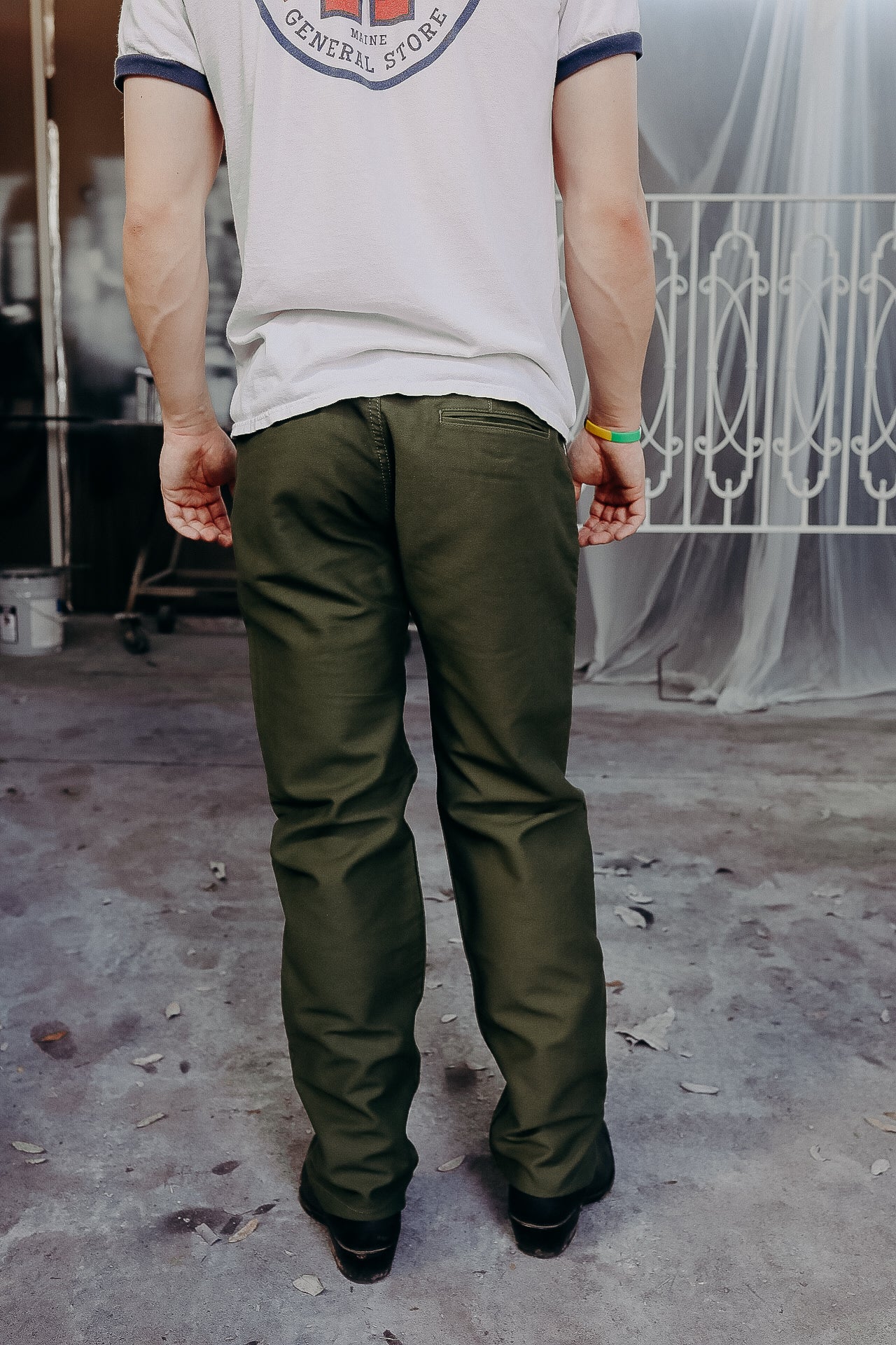 Man wearing olive green work pants and white graphic t-shirt standing on workshop concrete floor