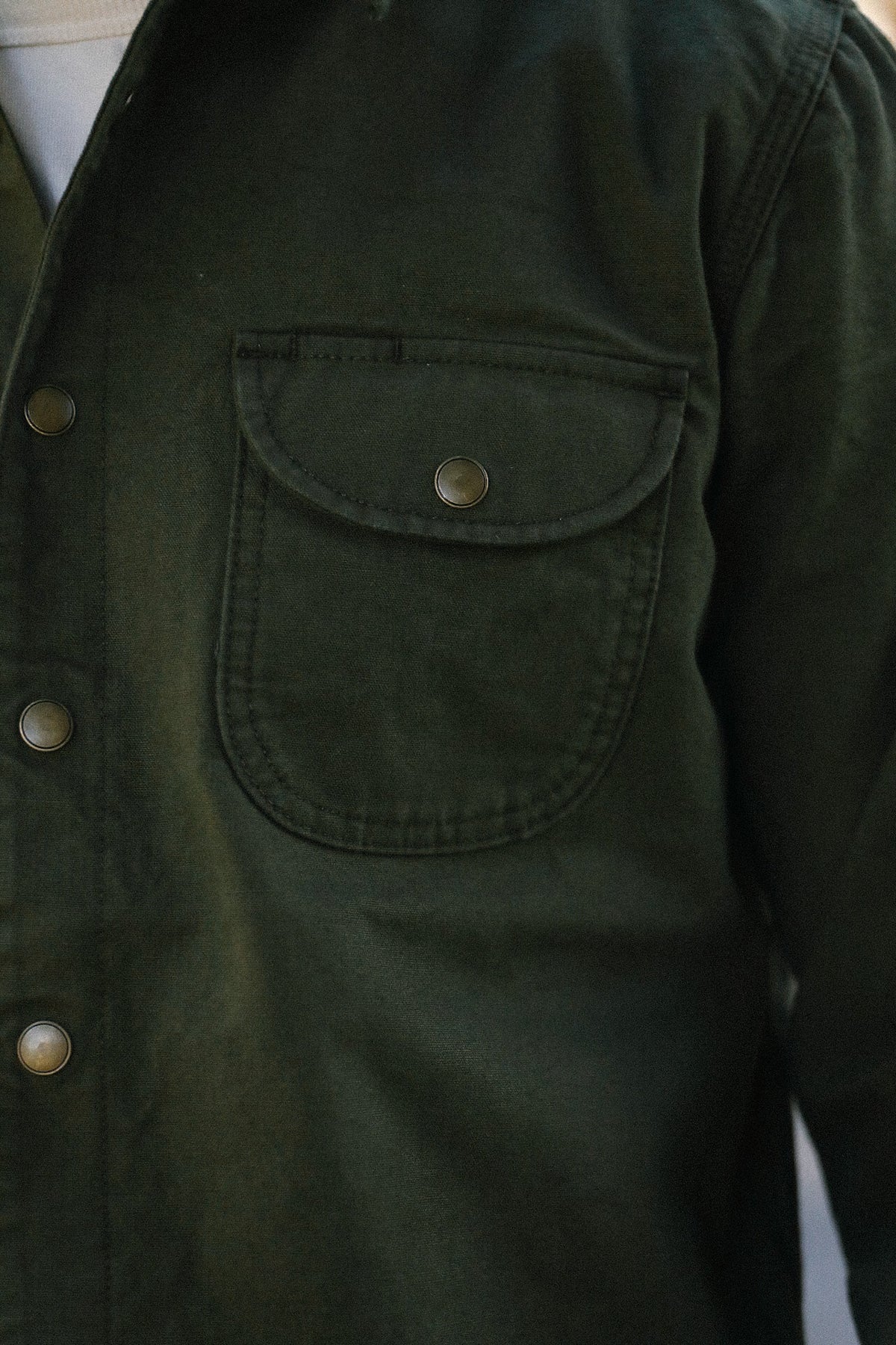 Close-up of dark green button-up work jacket with flap chest pocket and metal snap buttons