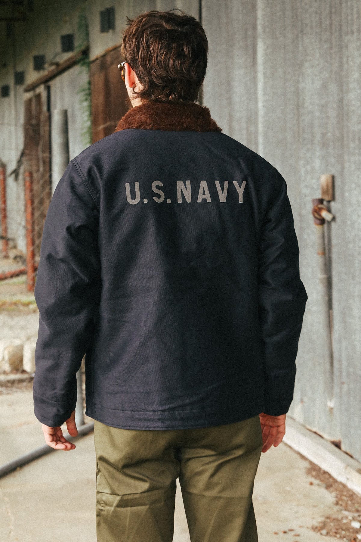 A man viewed from behind wearing a dark navy U.S.