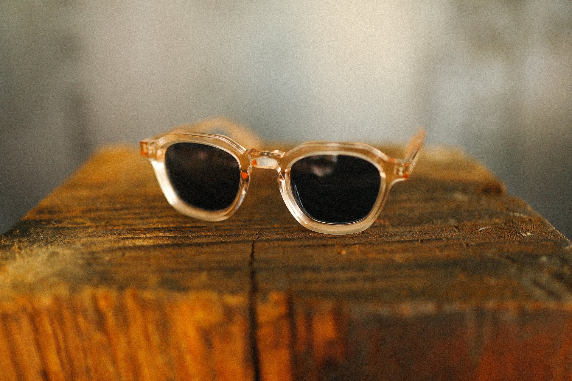 Clear frame sunglasses with dark lenses on rustic wooden surface at Iron Shop Provisions