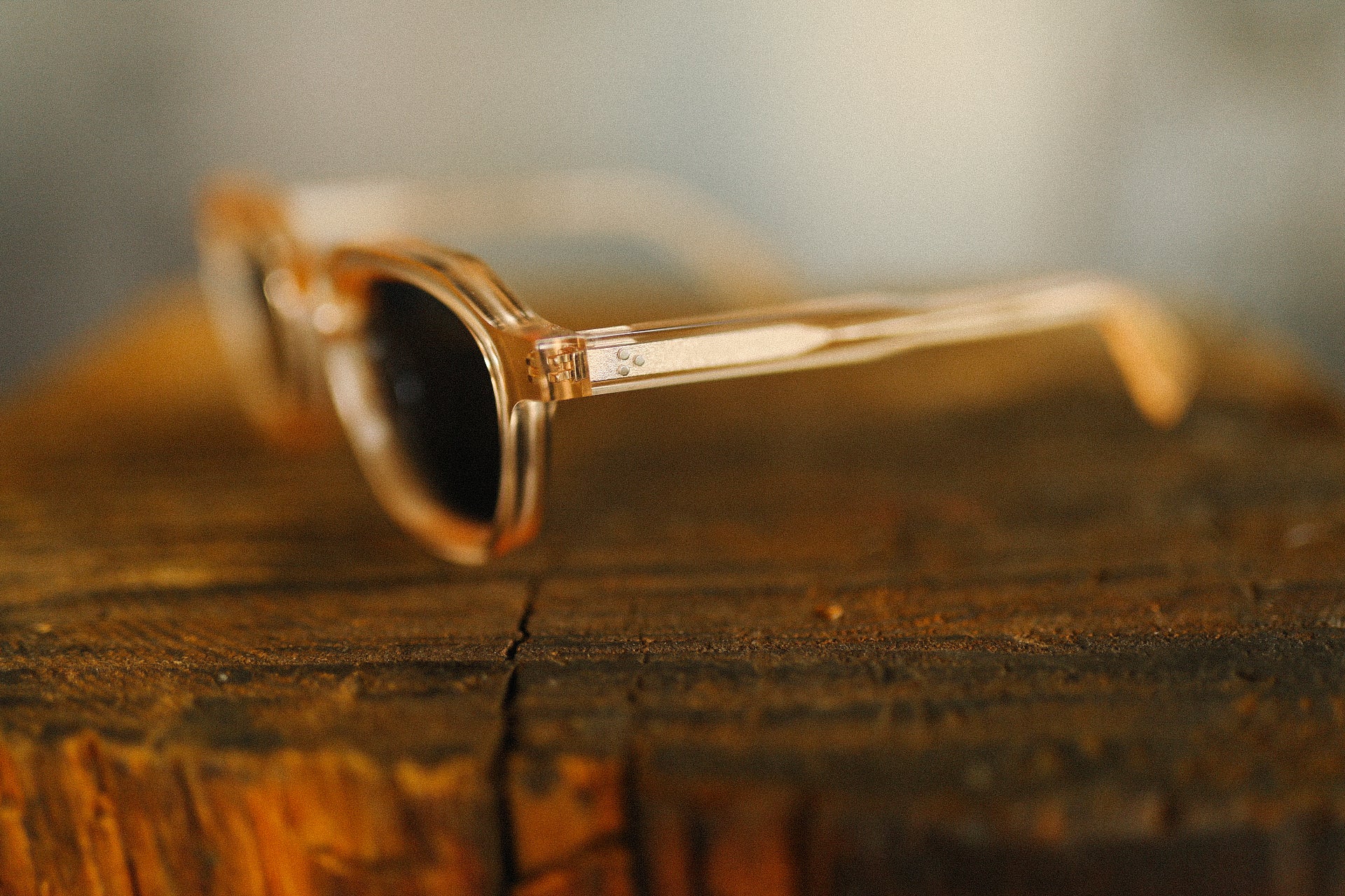 Close-up of amber translucent sunglasses with dark lenses on rustic wooden surface at Iron Shop Provisions
