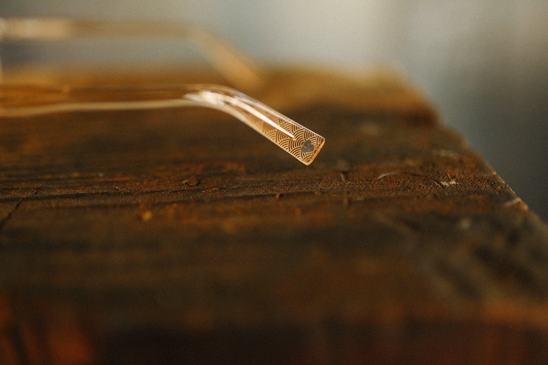 Close-up of a decorative metal tool with intricate patterns resting on a rustic wooden surface