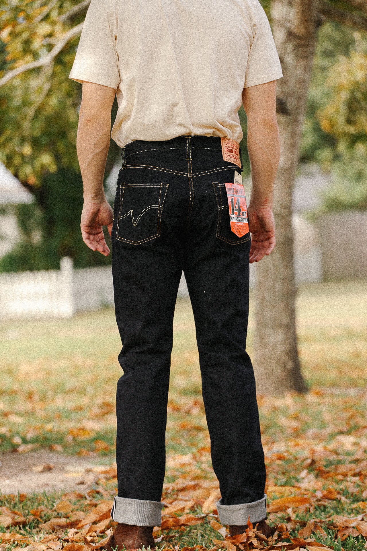 Back view of person wearing raw 14oz selvedge denim jeans with cuff and tan boots outdoors