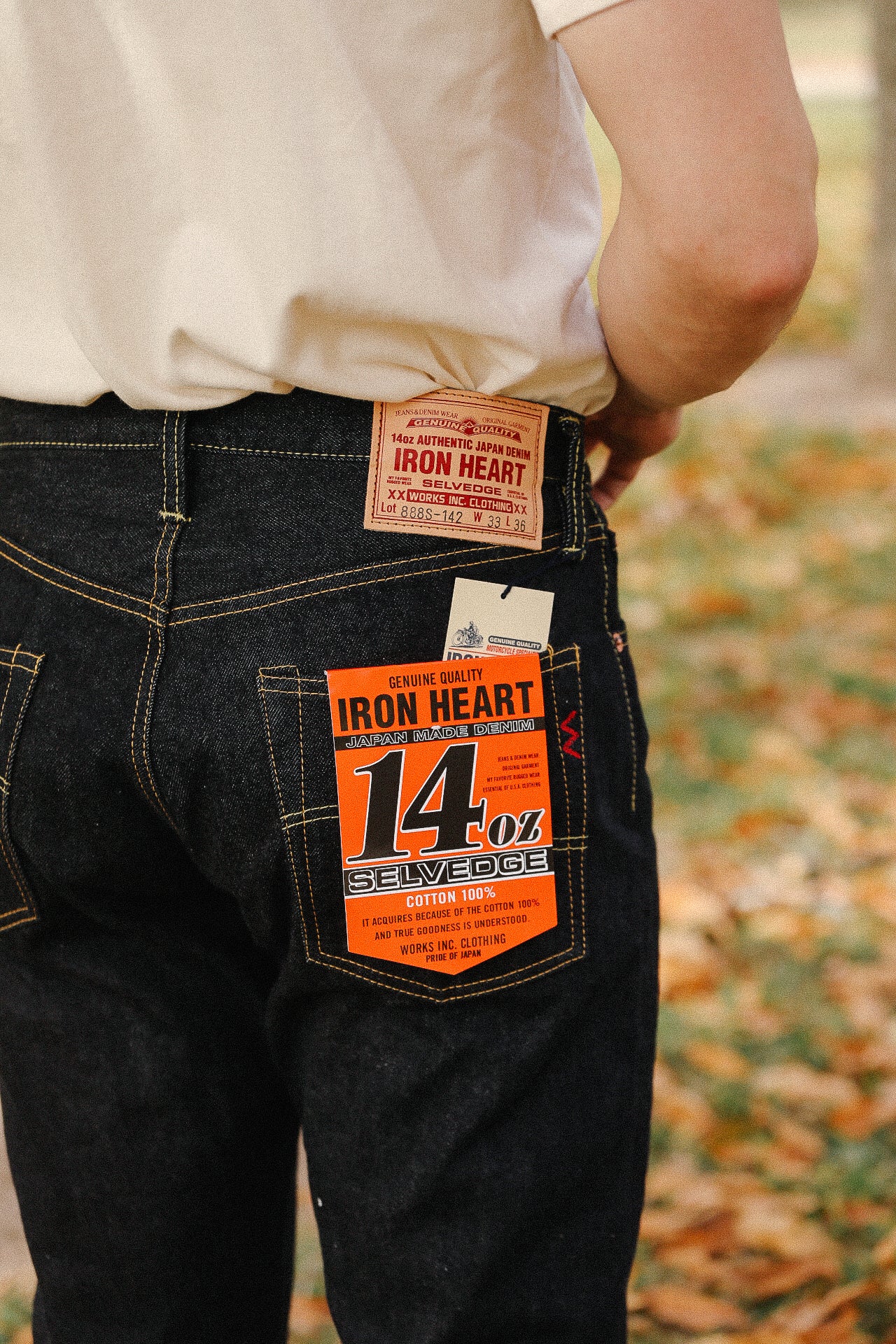 Close-up of person wearing Iron Heart 14oz selvedge denim jeans with distinctive label patch on back pocket