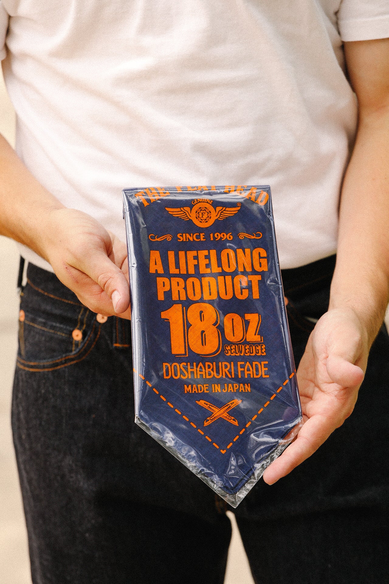 Person holding packaged 18 oz selvedge denim labeled Doshaburi Fade, made in Japan