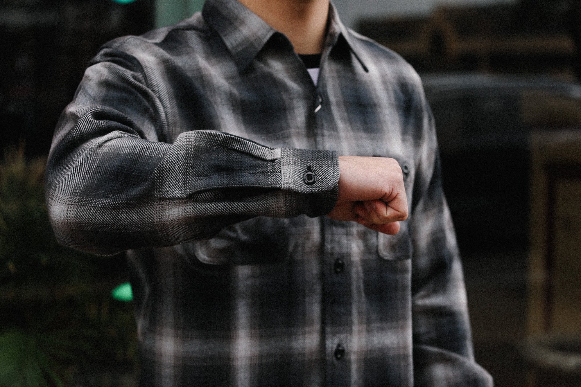 Person wearing a gray plaid flannel shirt from Iron Shop Provisions with sleeve button detail