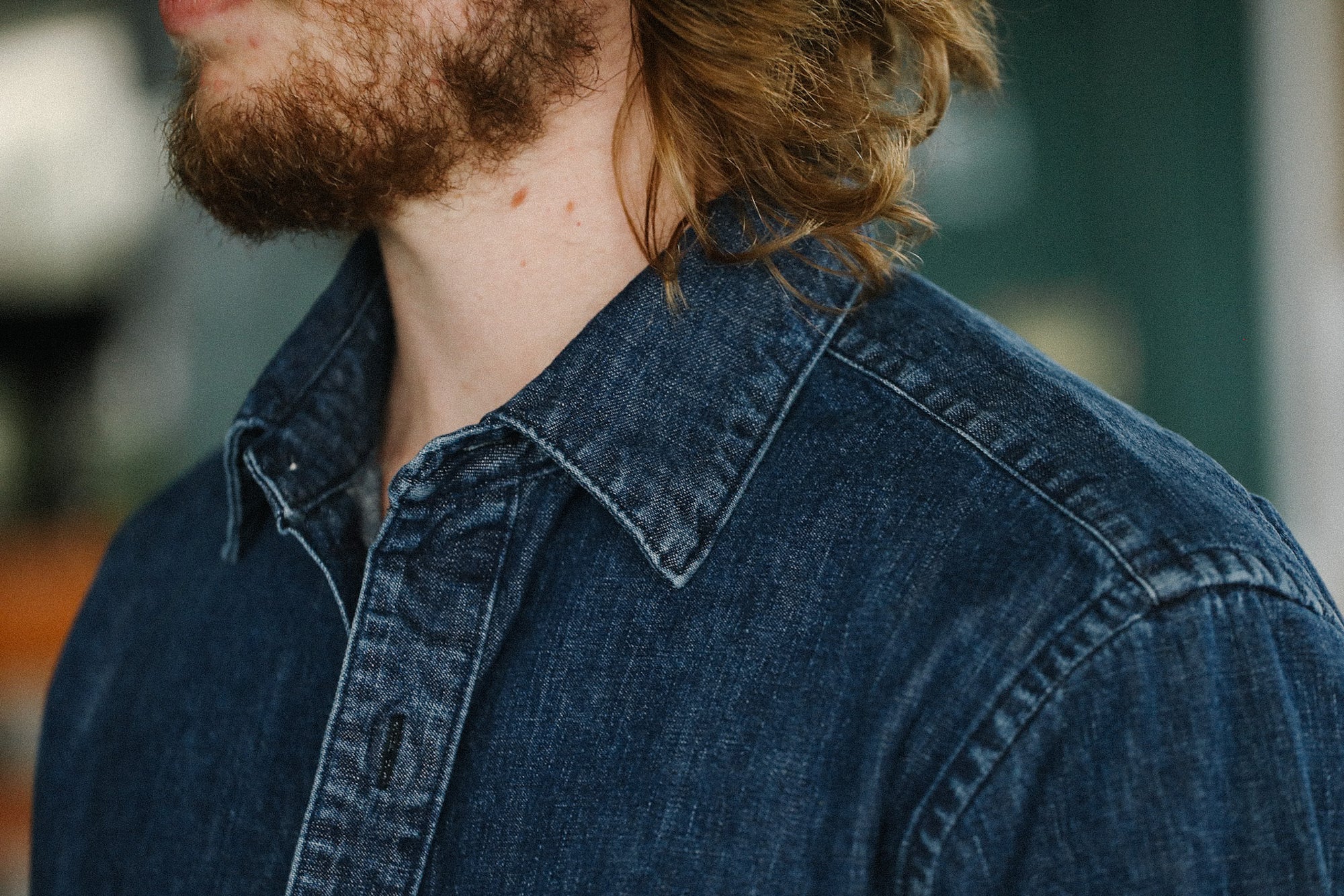 Close-up of a man with beard wearing a blue denim shirt with detailed stitching