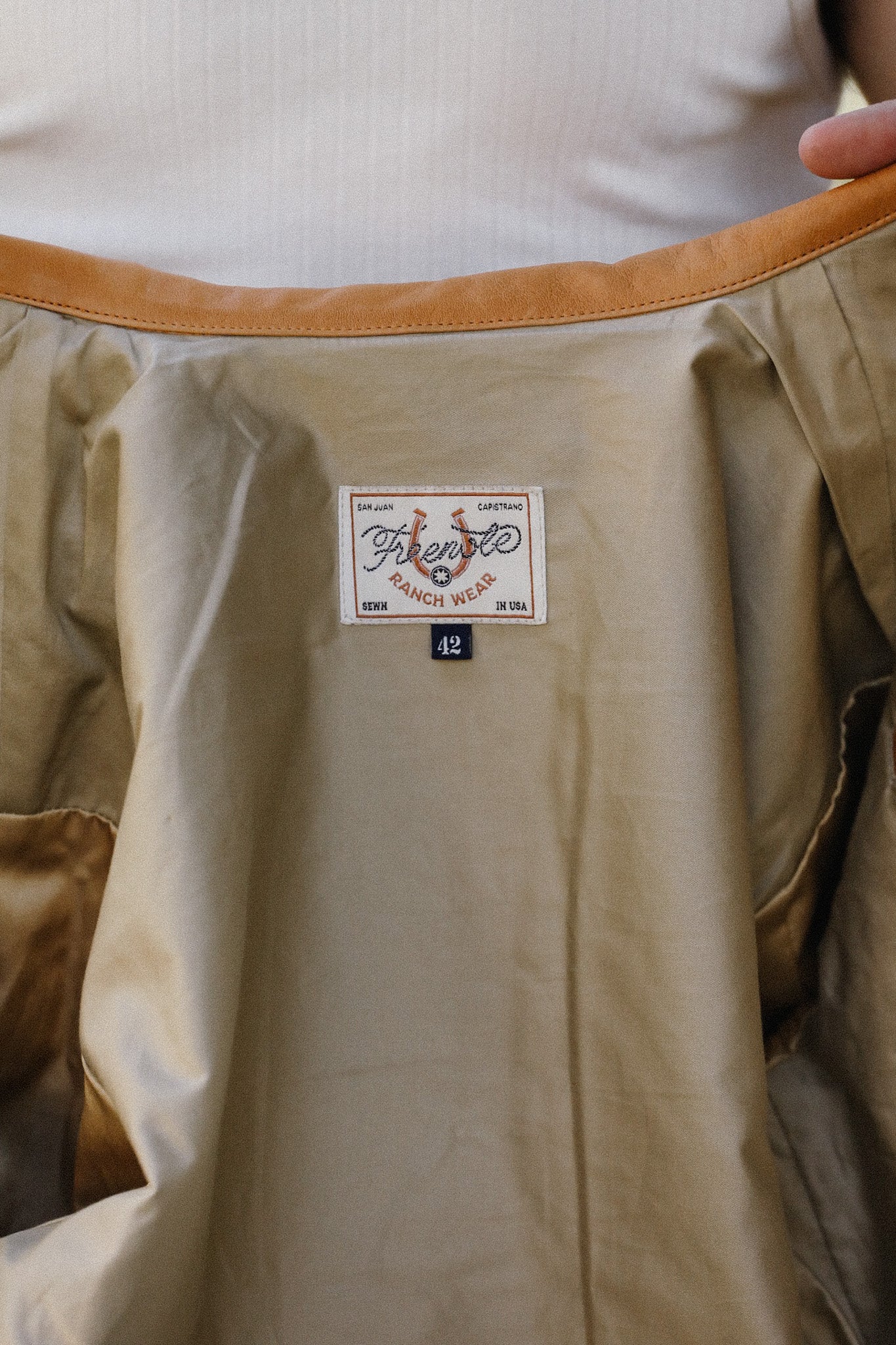 Close-up of khaki jacket interior with leather collar and French Ranch Wear label size 42