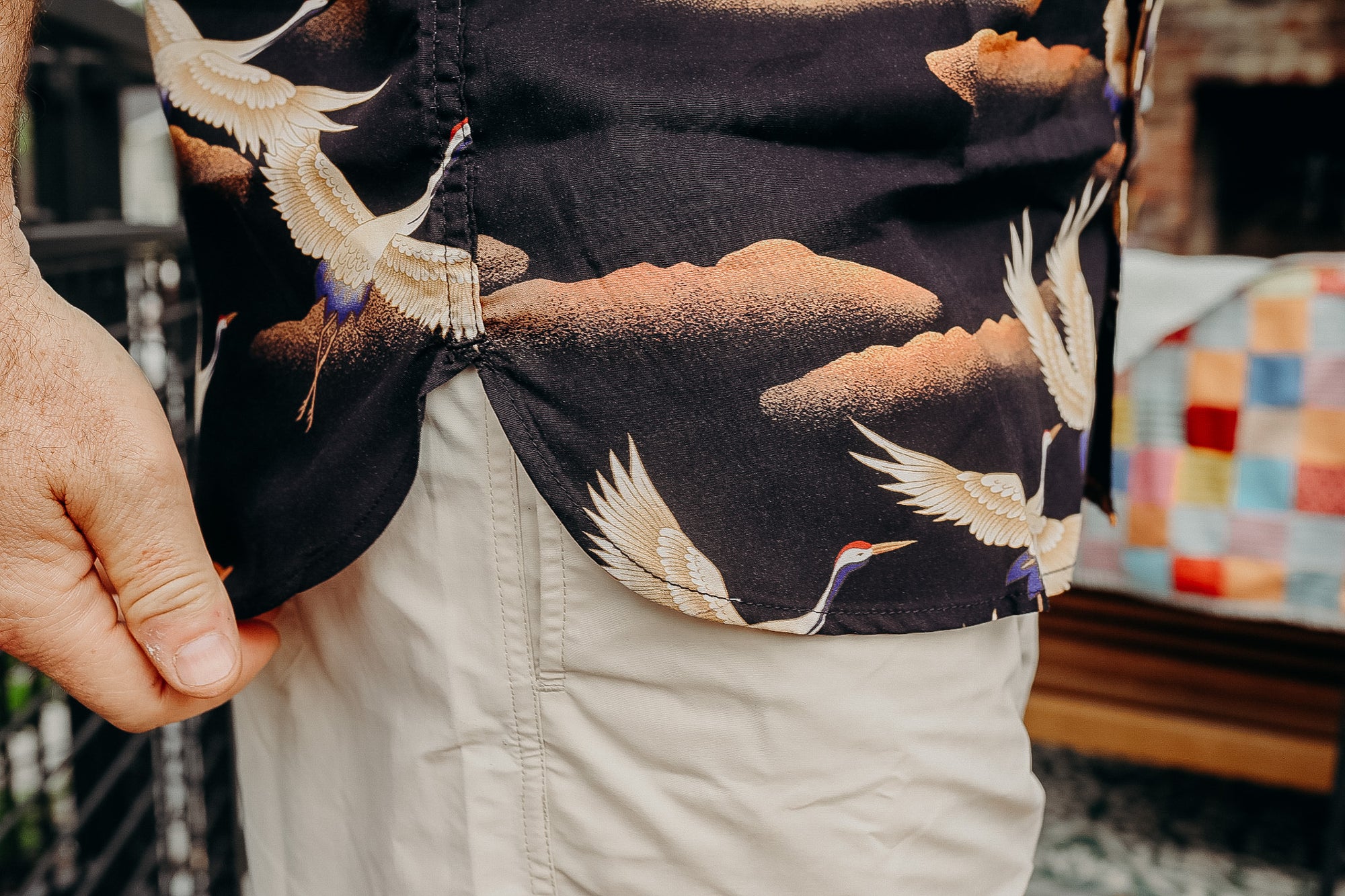 Close-up of black shirt with crane bird print and beige pants in casual setting