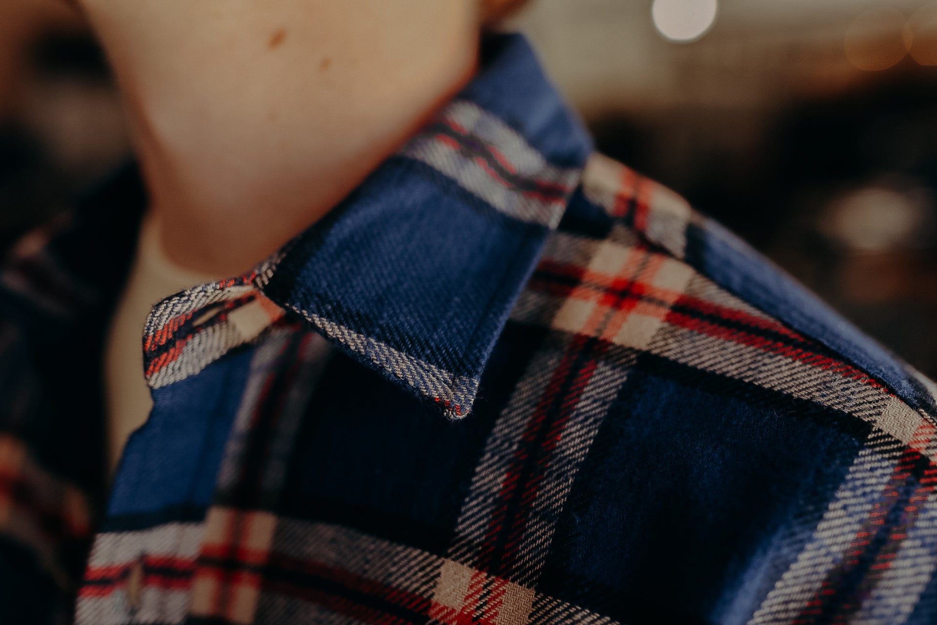 Close-up of blue and red plaid flannel shirt collar on person wearing a white undershirt