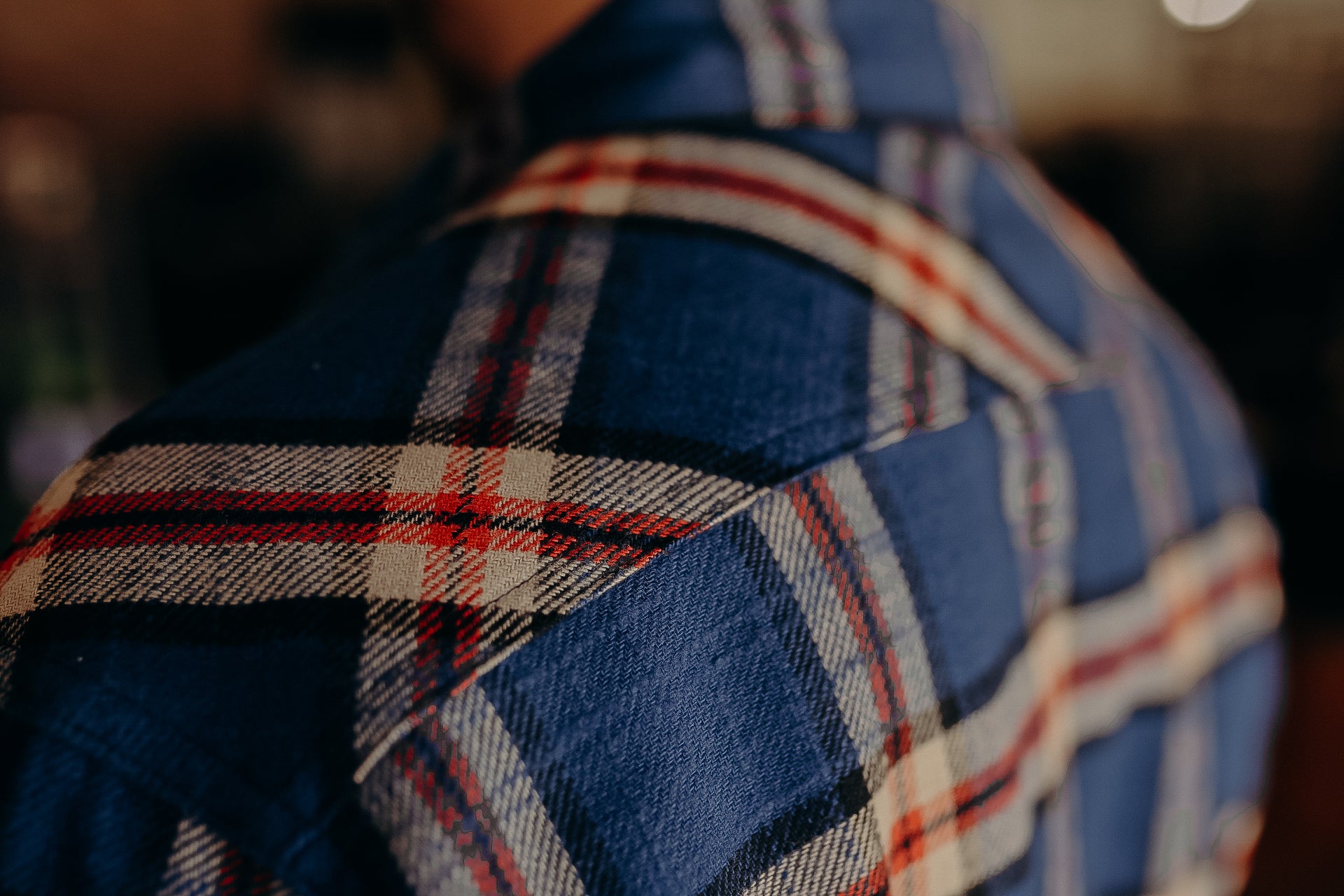 Close-up of blue and red plaid flannel shirt shoulder detail at Iron Shop Provisions
