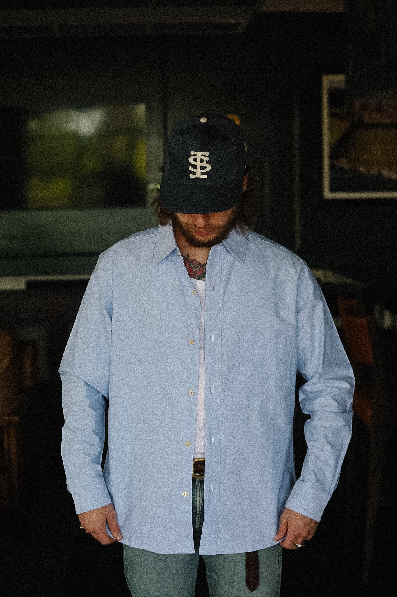 Man wearing a light blue shirt and black cap indoors