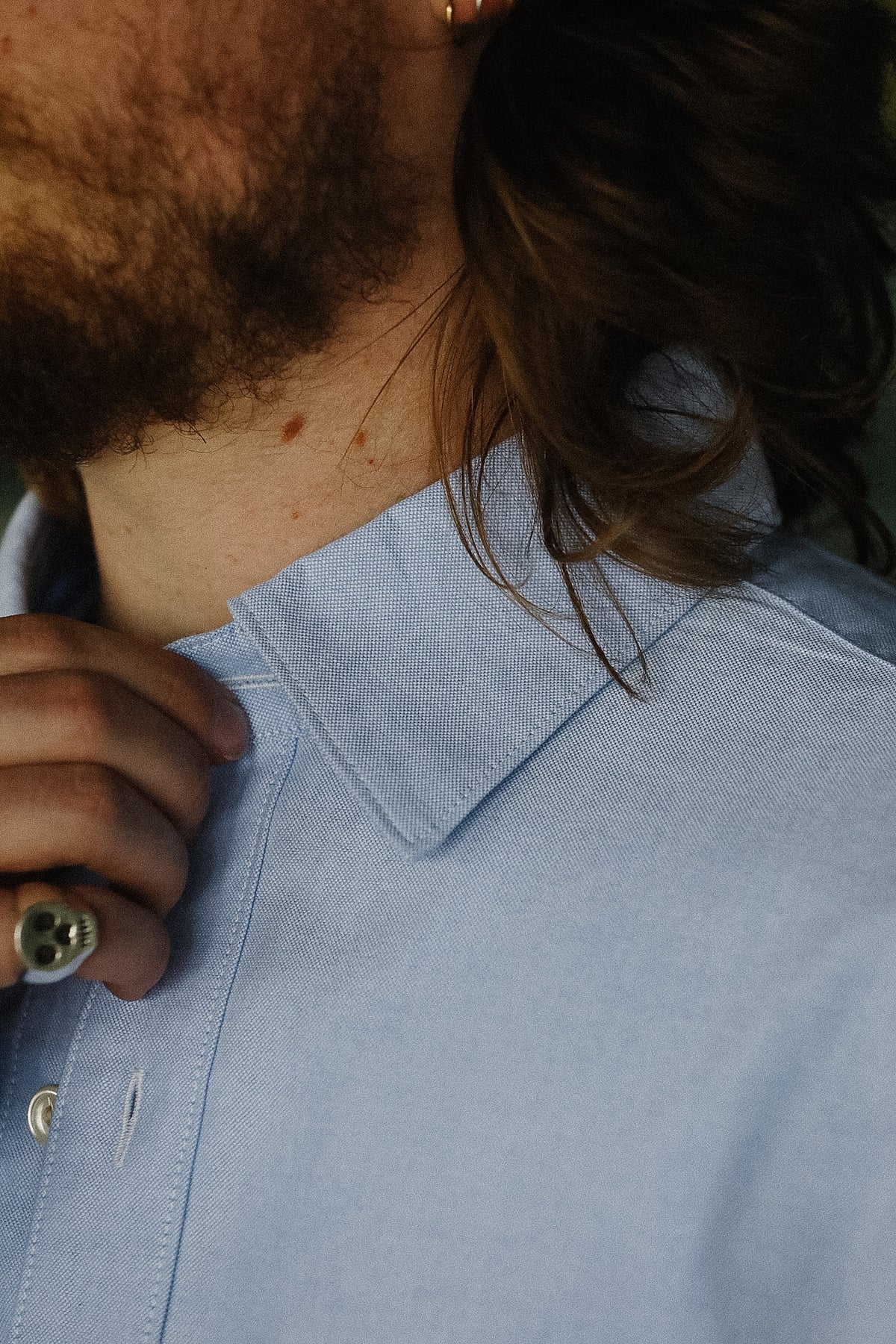 Close-up of a person wearing a light blue shirt with a collar.