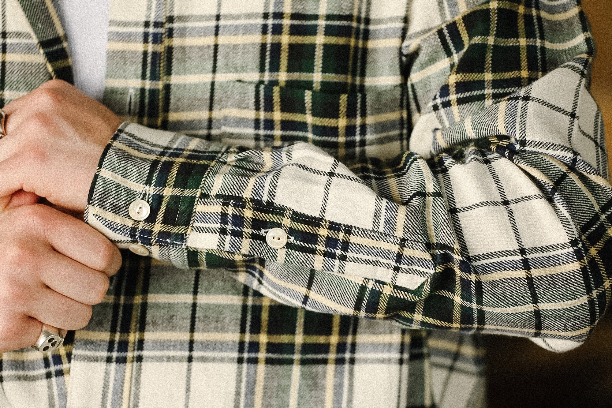 Close-up of a plaid shirt with rolled-up sleeves and a blurred background