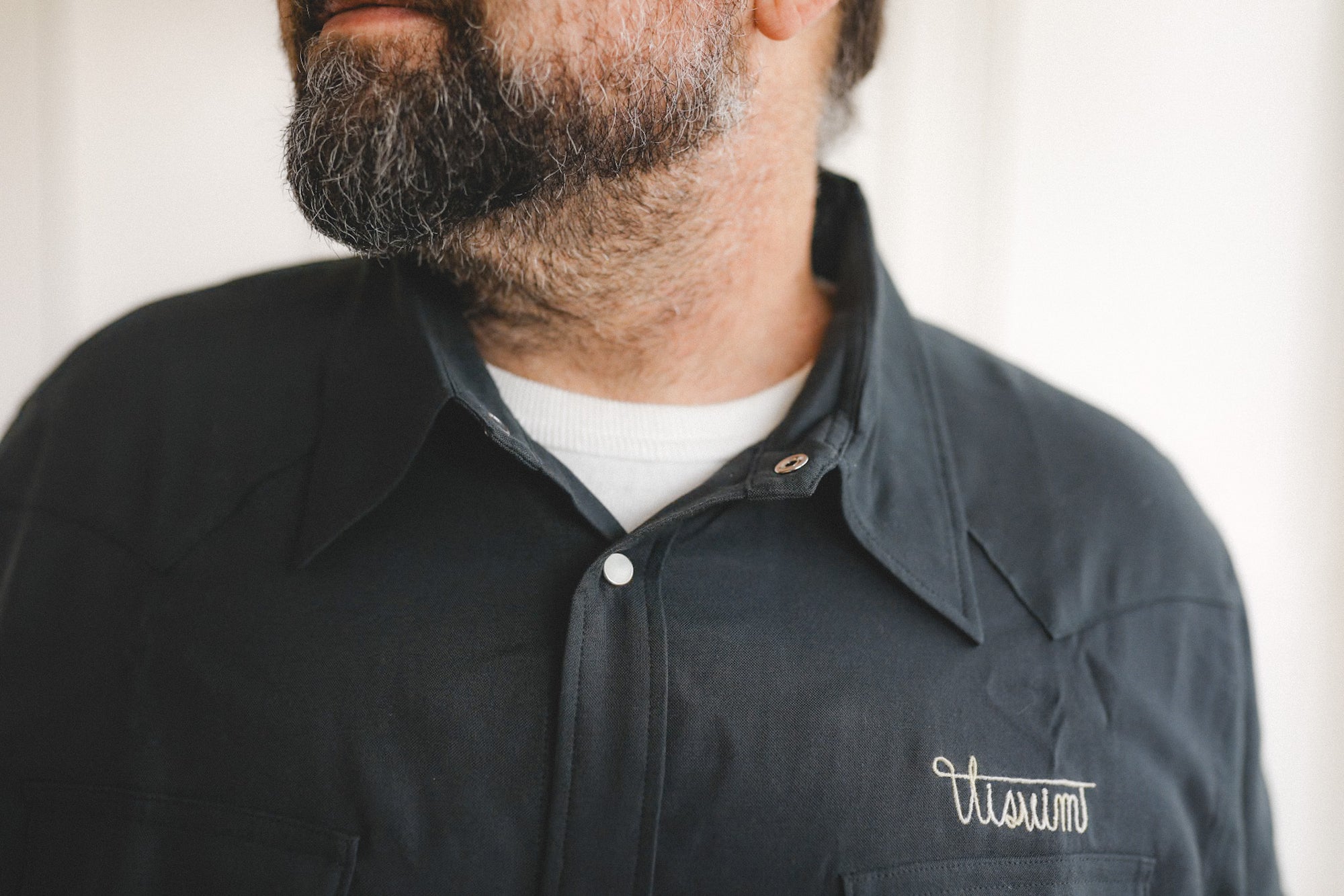 Man wearing a black jacket with 'Vissim' logo on a neutral background