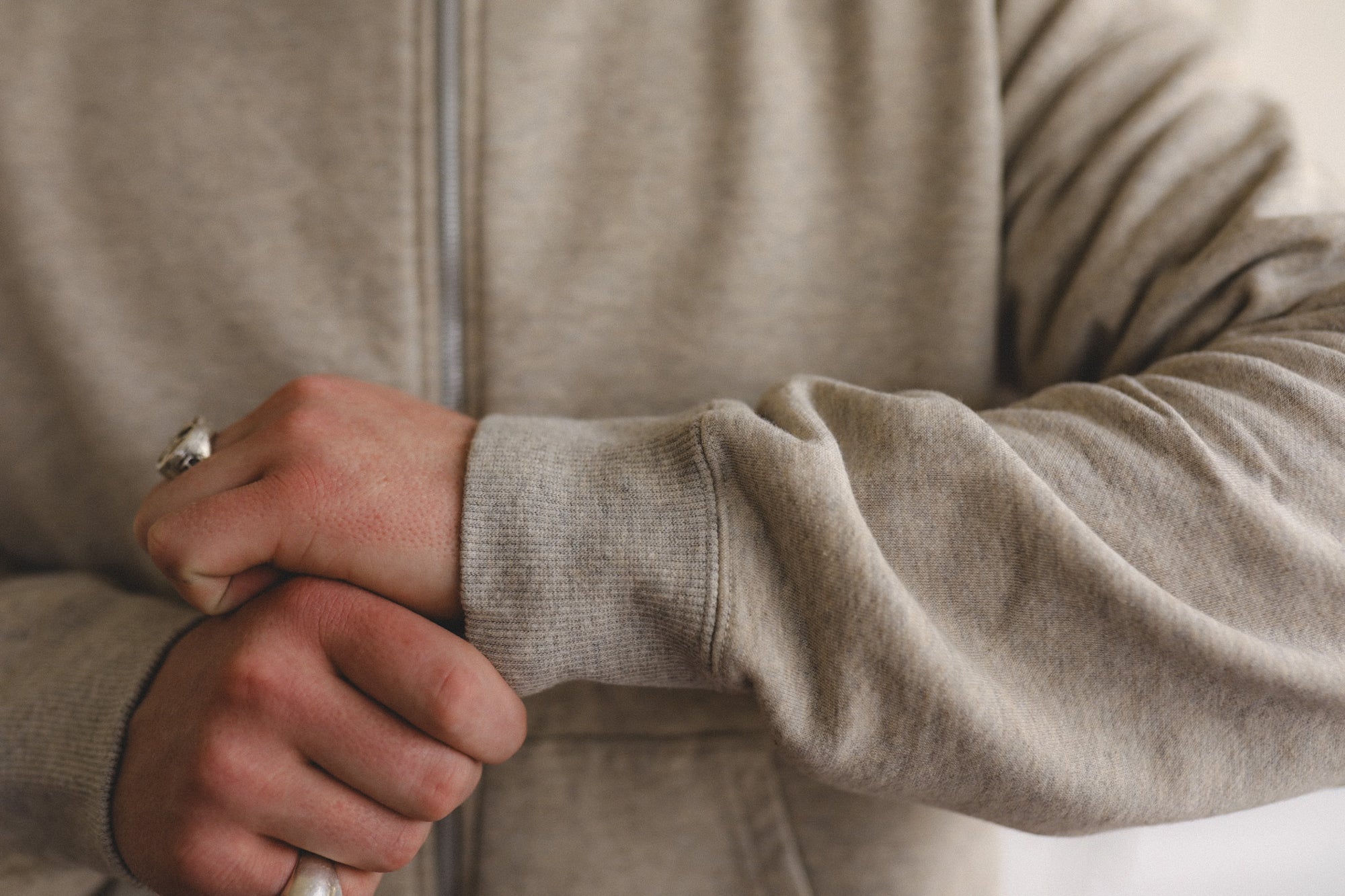 Close-up of a person wearing a beige sweater with a neutral background