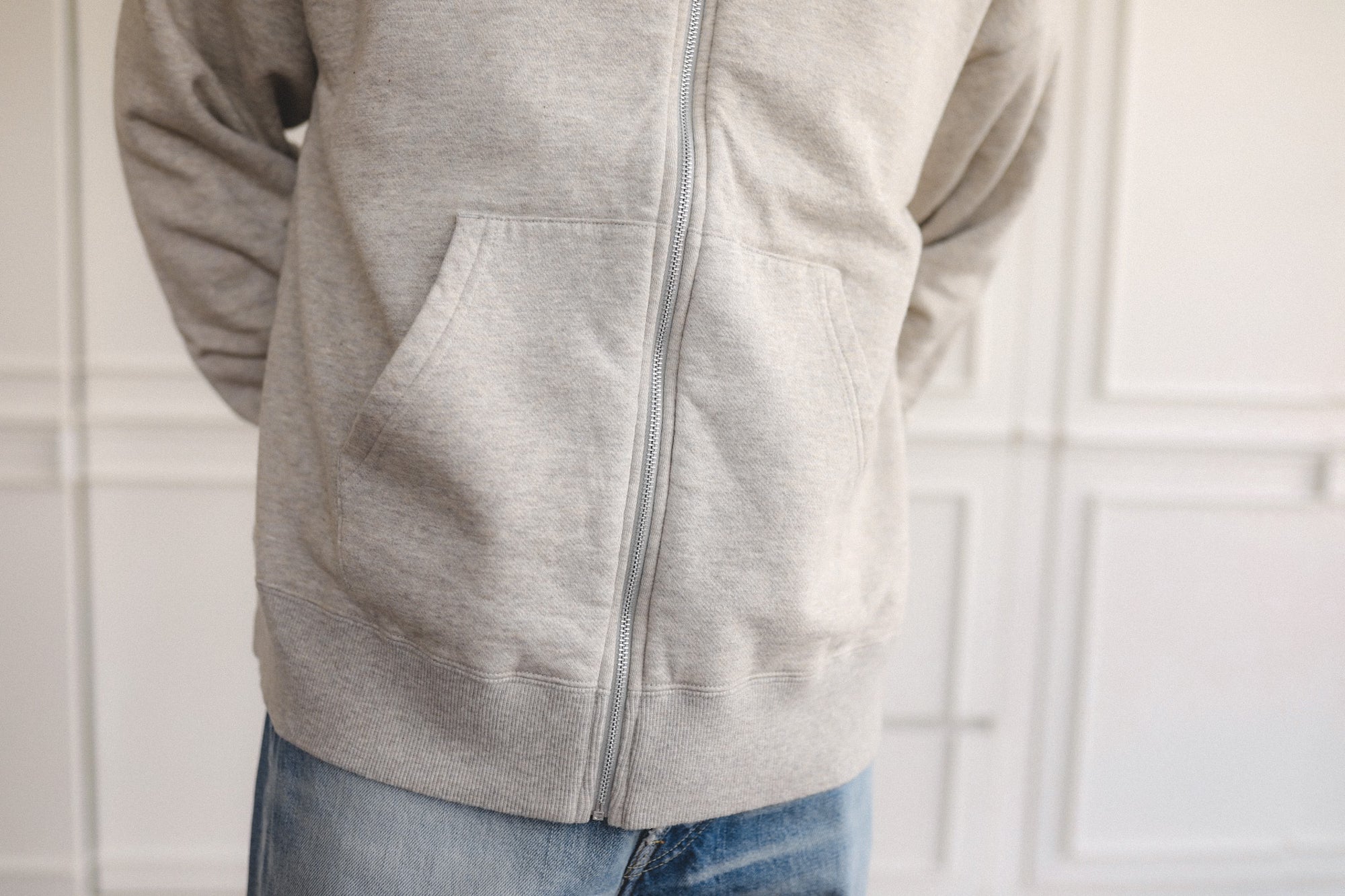 Person wearing a gray zip-up hoodie with a neutral background